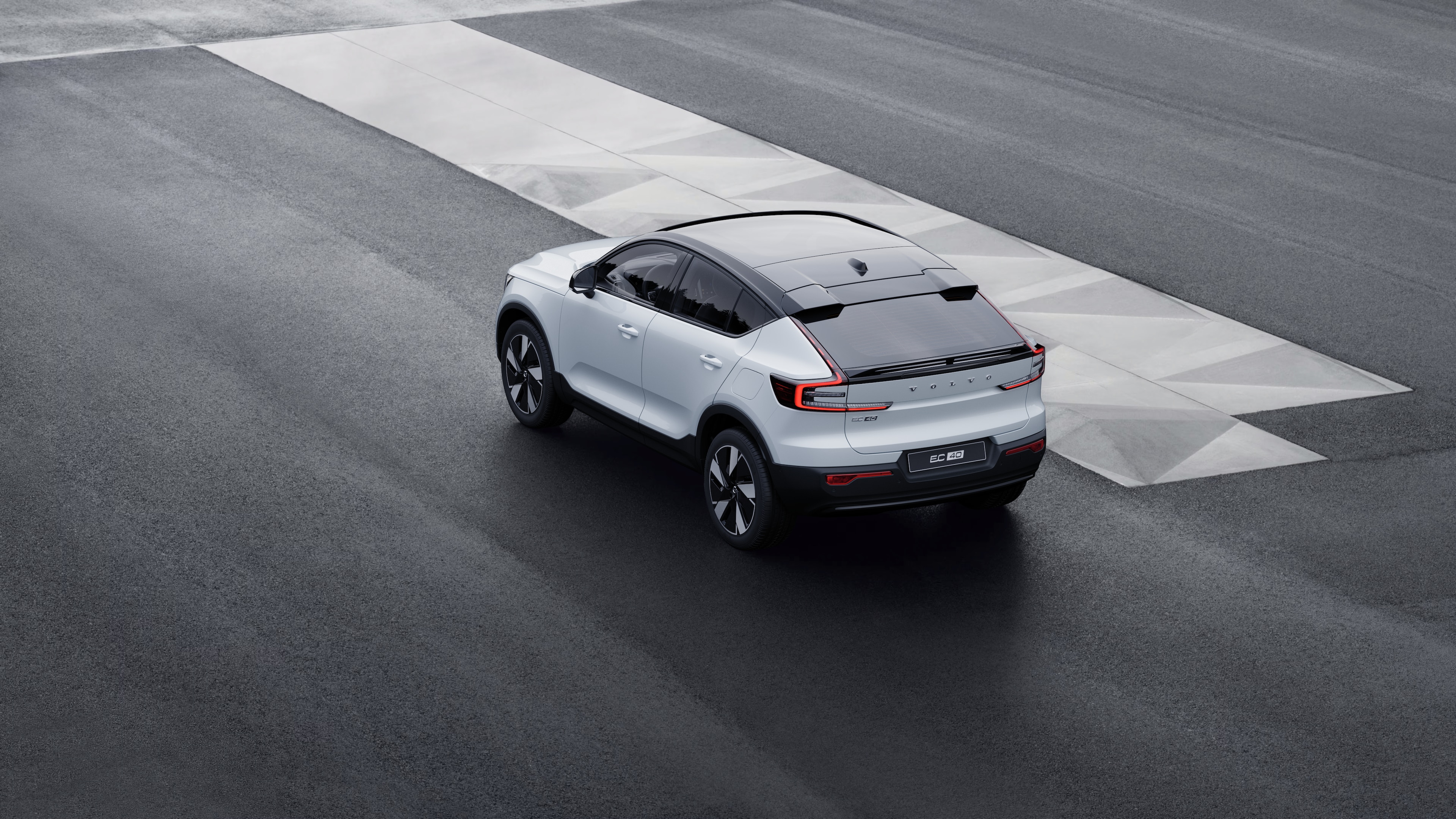 Samochód Volvo w widoku z tyłu w trzech czwartych zaparkowany przy murze na tle miejskiej ulicy