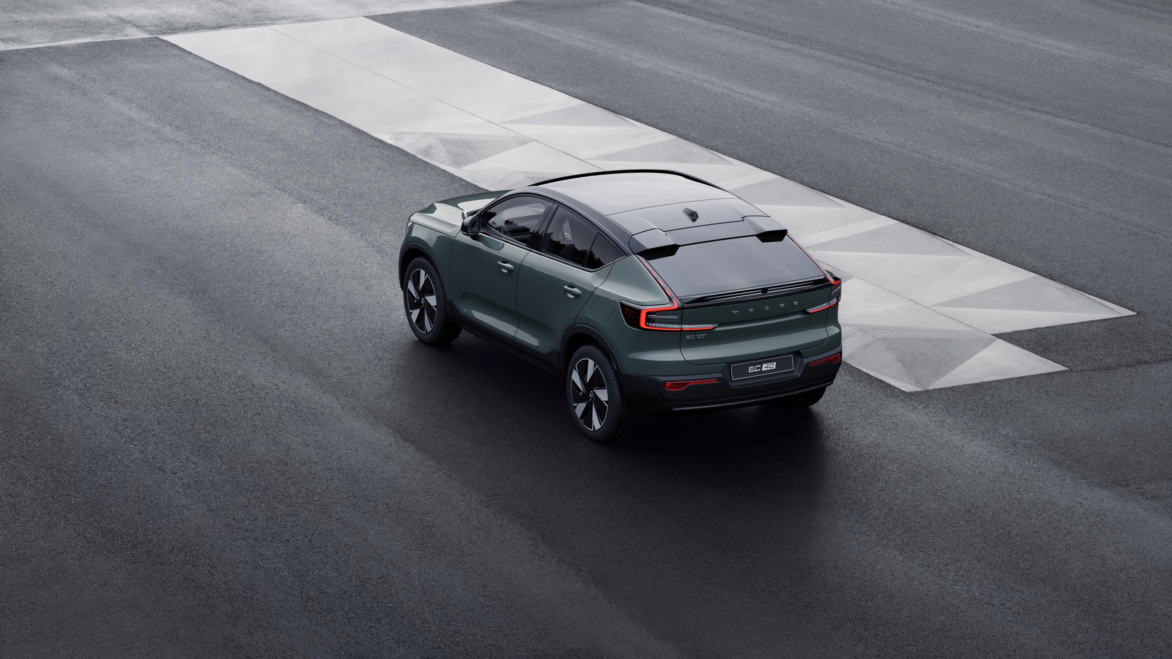 Volvo car in rear three-quarter view parked against a concrete wall on an urban street background.