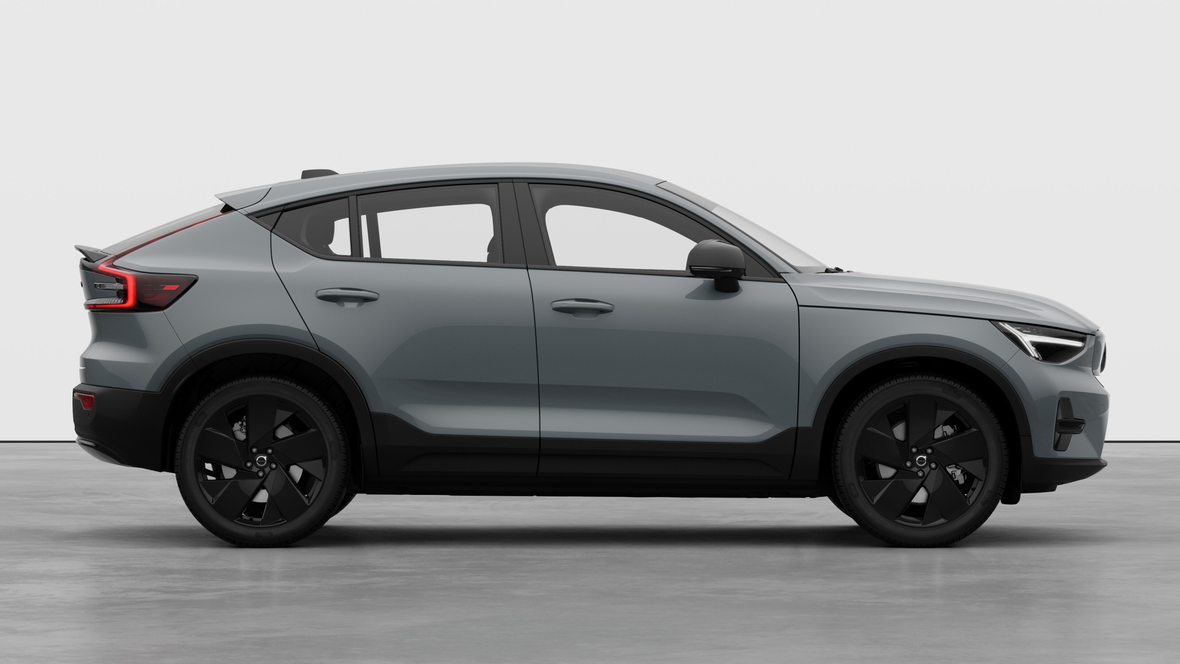 Seitenansicht eines Volvo Fahrzeugs auf einem schlichten Studiohintergrund mit geschlossenen Türen und sichtbarem Raddesign.