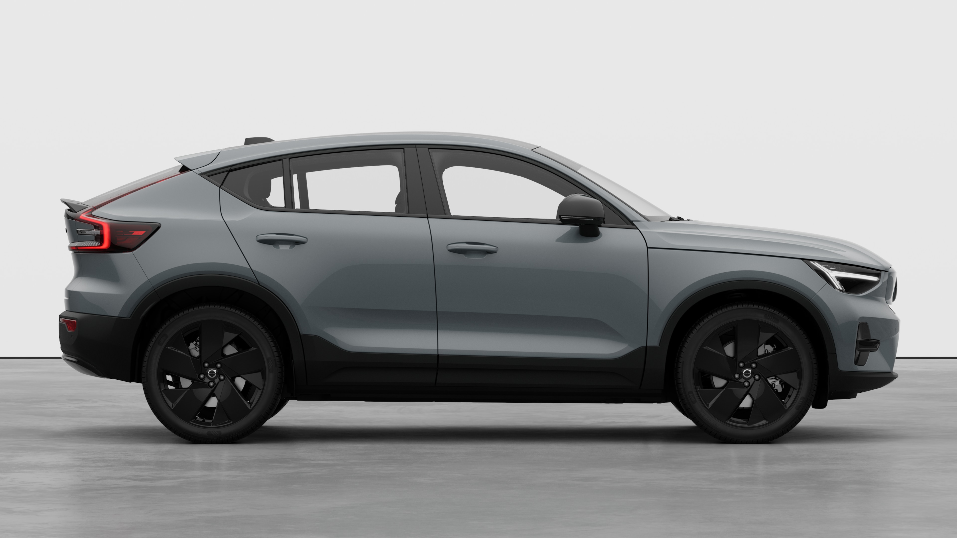 Seitenansicht eines Volvo Fahrzeugs auf einem schlichten Studiohintergrund mit geschlossenen Türen und sichtbarem Raddesign.