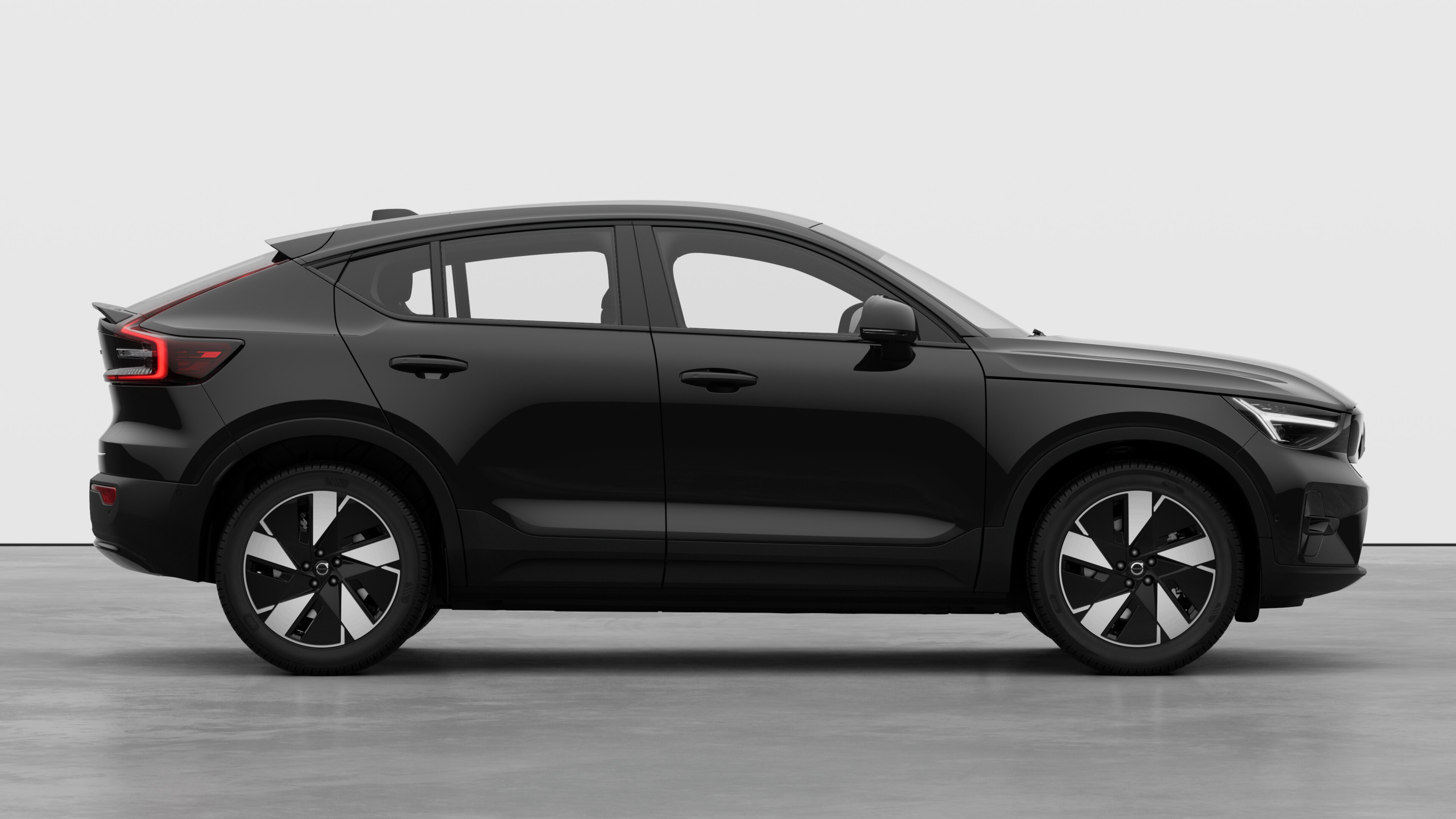 Volvo car side view on plain studio background displaying closed doors and visible wheel design.