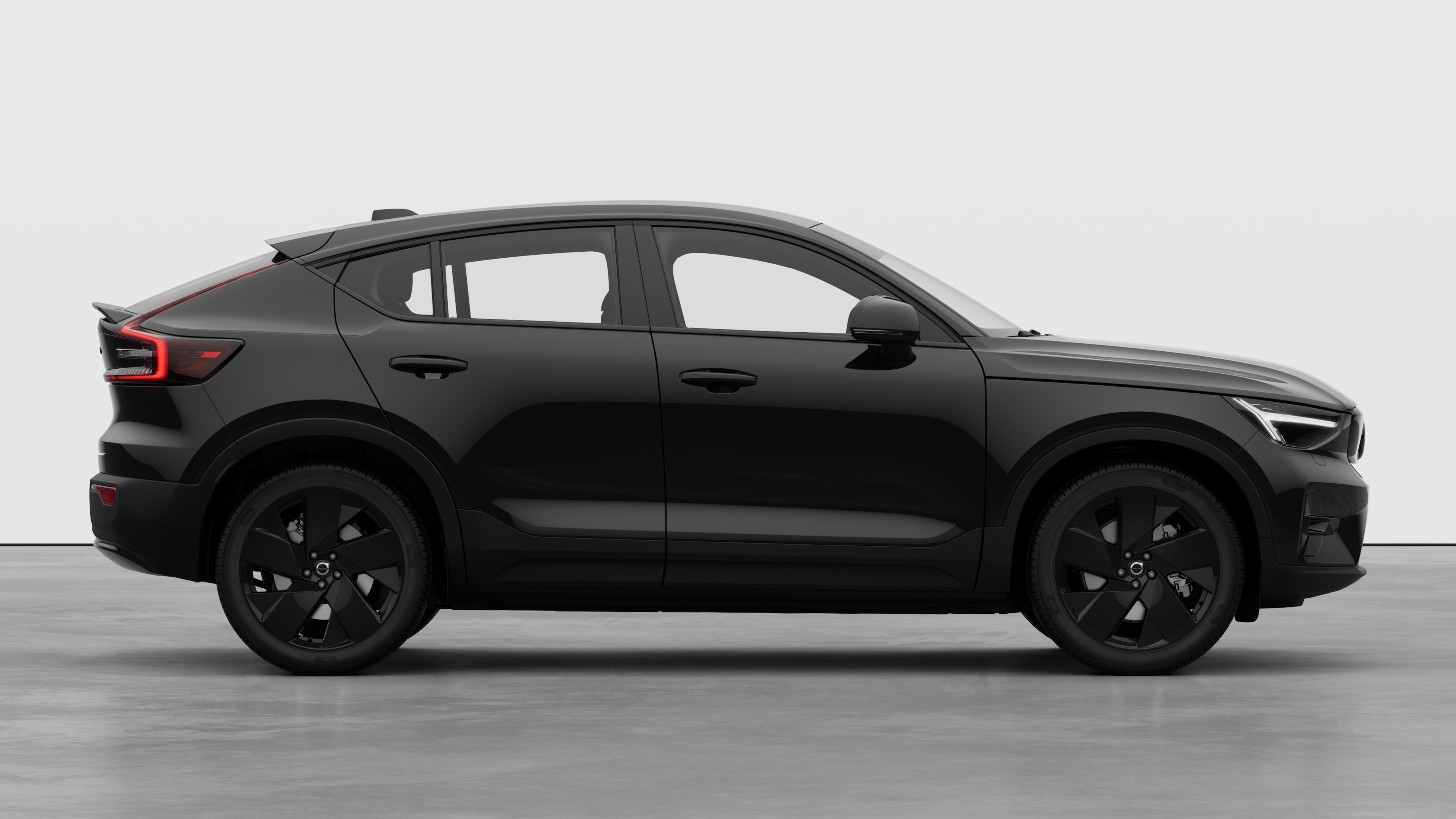 Sidovy från Volvo-bilen på en vanlig studiobakgrund som visar stängda dörrar och synlig fälgdesign.