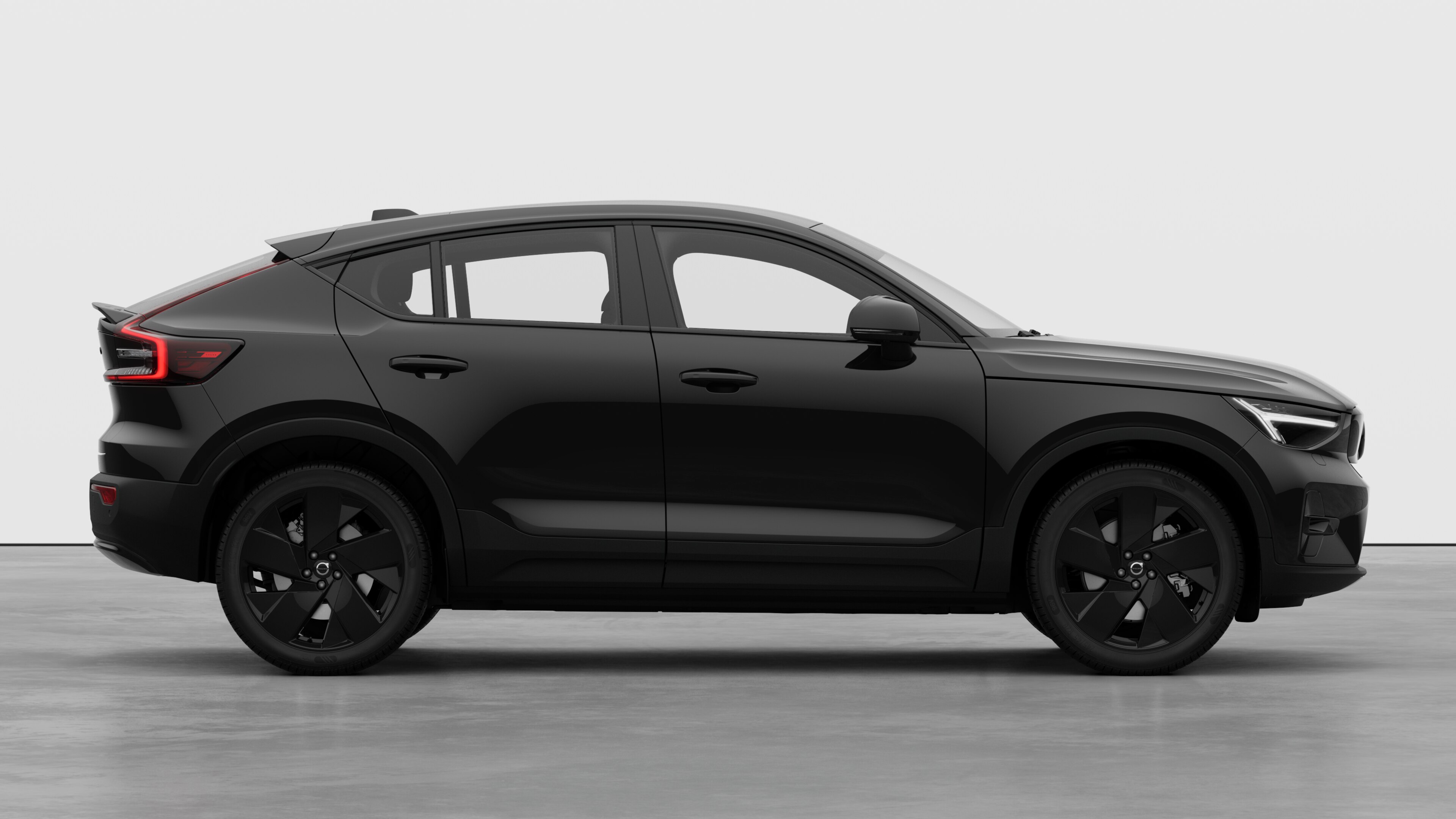 Sidovy från Volvo-bilen på en vanlig studiobakgrund som visar stängda dörrar och synlig fälgdesign.