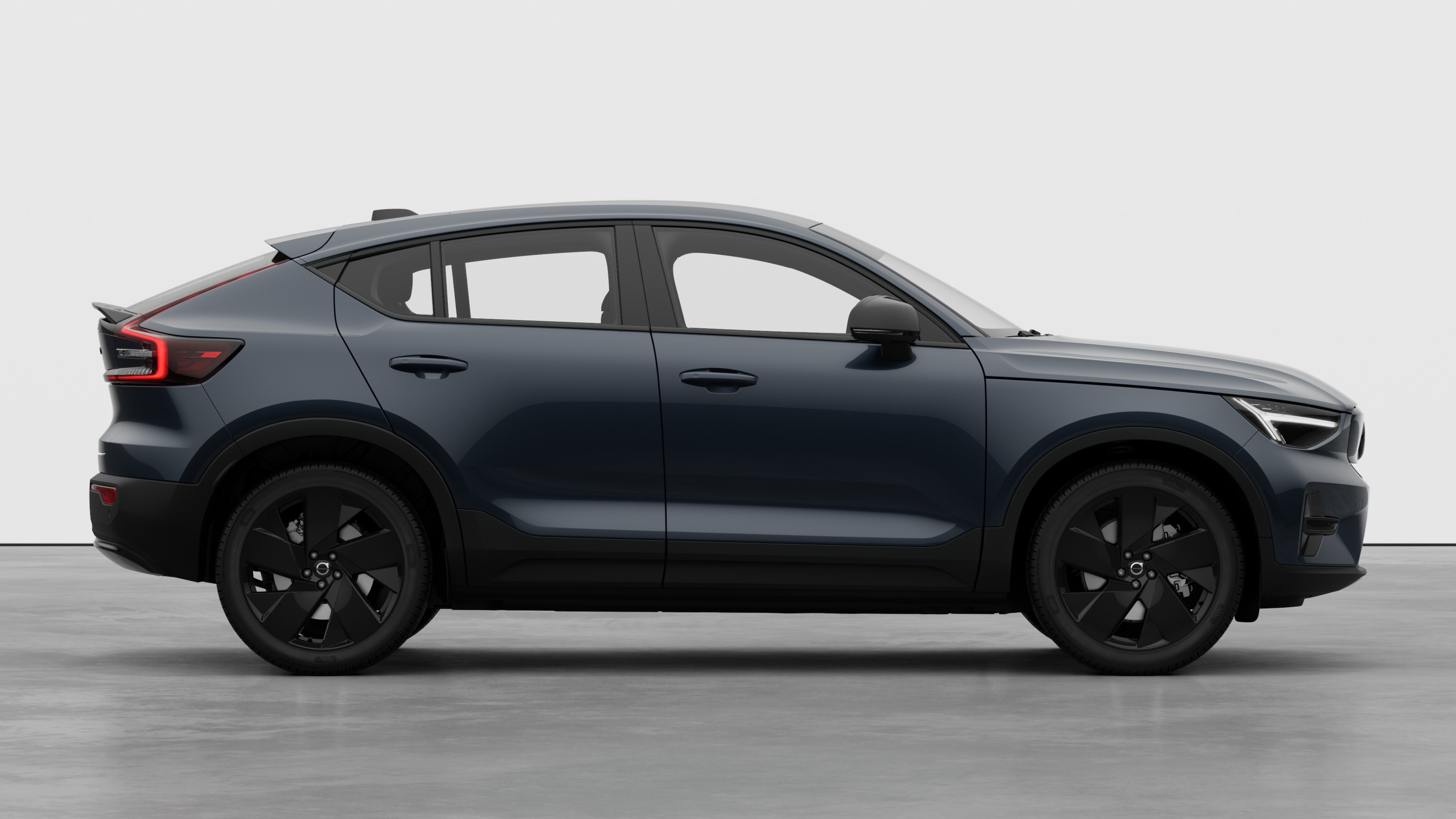 Seitenansicht eines Volvo Fahrzeugs auf einem schlichten Studiohintergrund mit geschlossenen Türen und sichtbarem Raddesign.