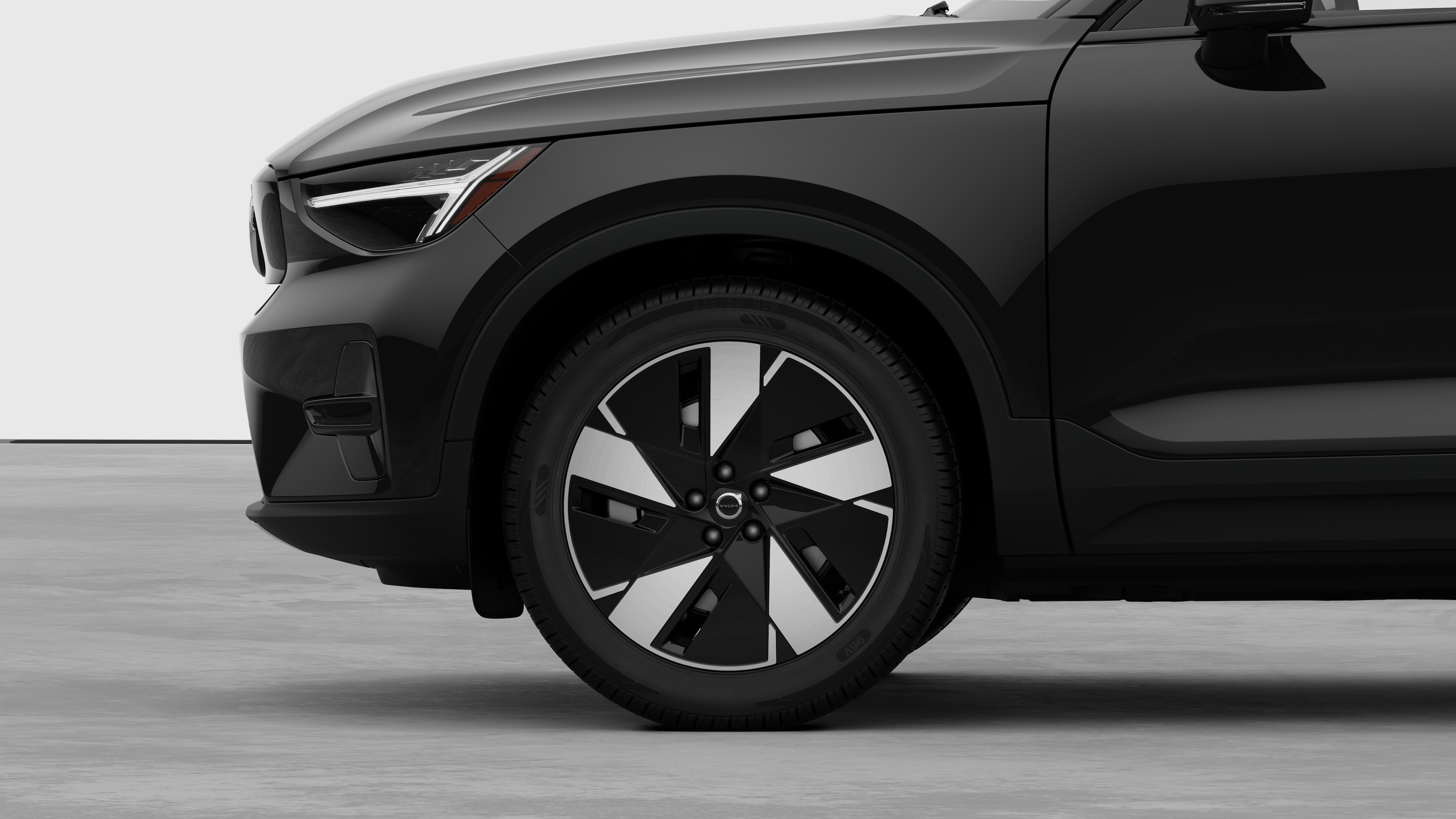 Vista lateral exterior del vehículo Volvo centrada en la rueda delantera y el guardabarros, sobre un fondo de estudio liso.