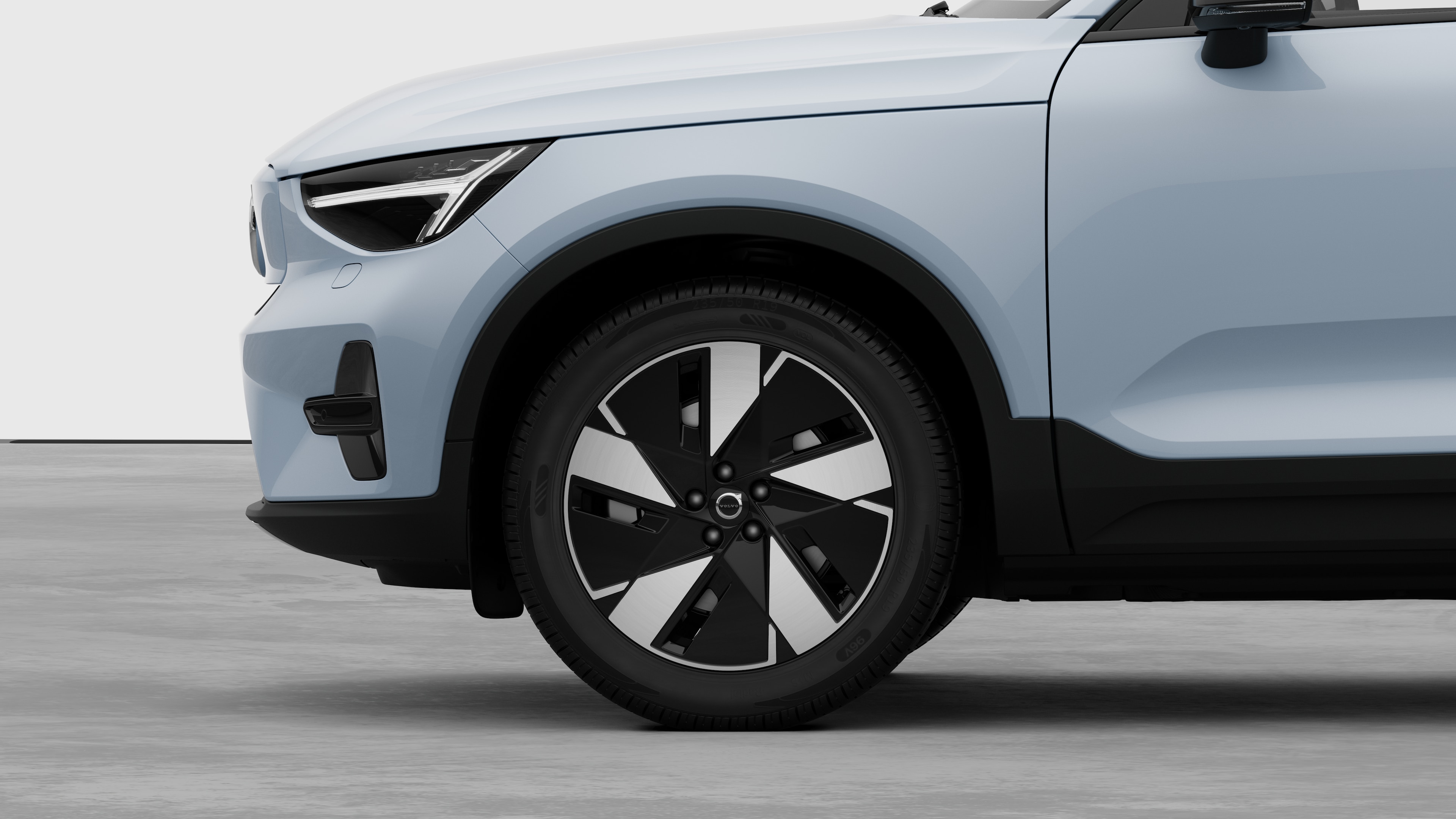 Volvo-auton sivunäkymä ulkopuolelta keskittyen etupyörään ja lokasuojaan studiotaustaa vasten.