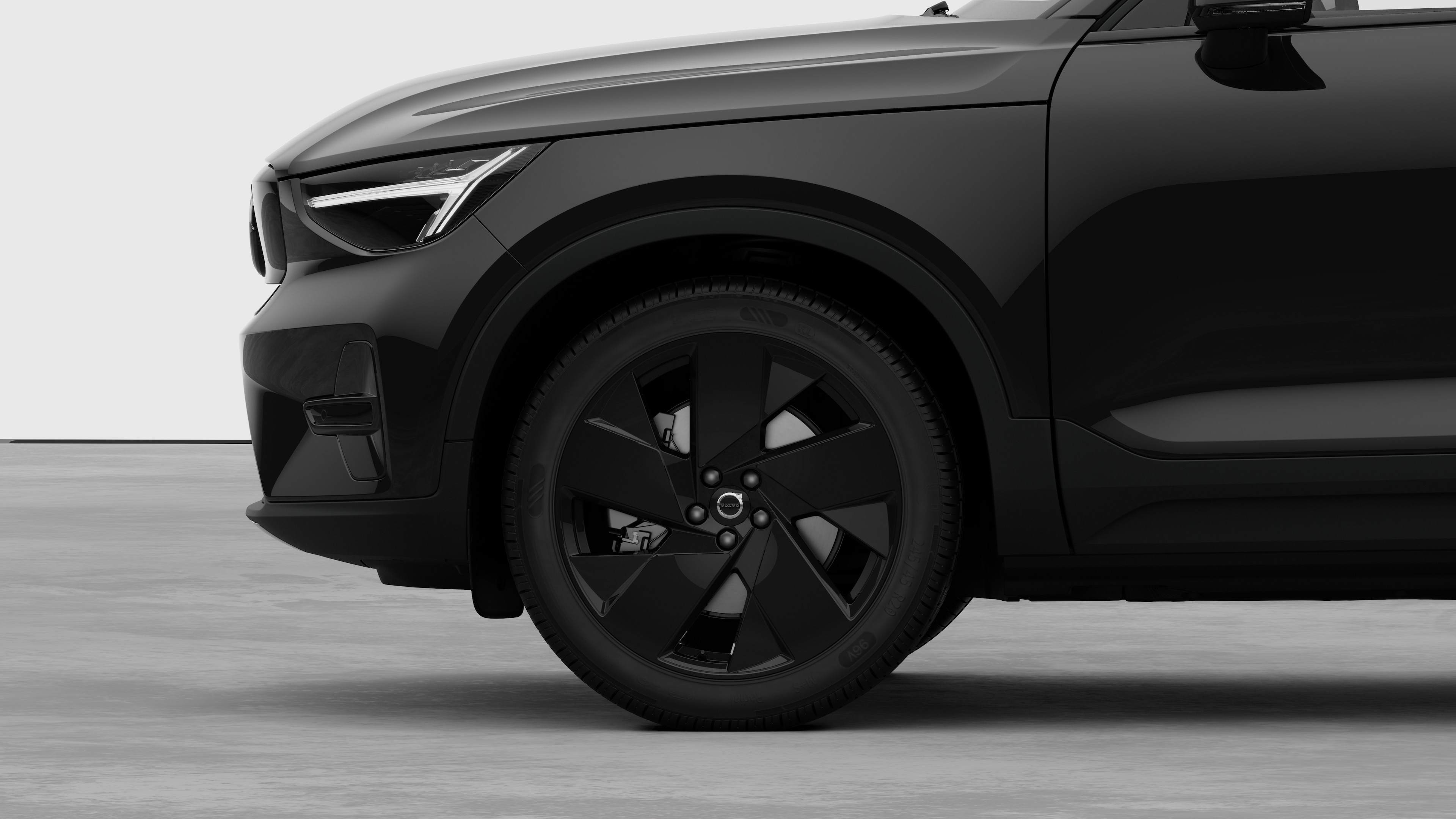 Vista lateral exterior do automóvel Volvo centrada na roda dianteira e no guarda-lamas, contra um fundo de estúdio simples.