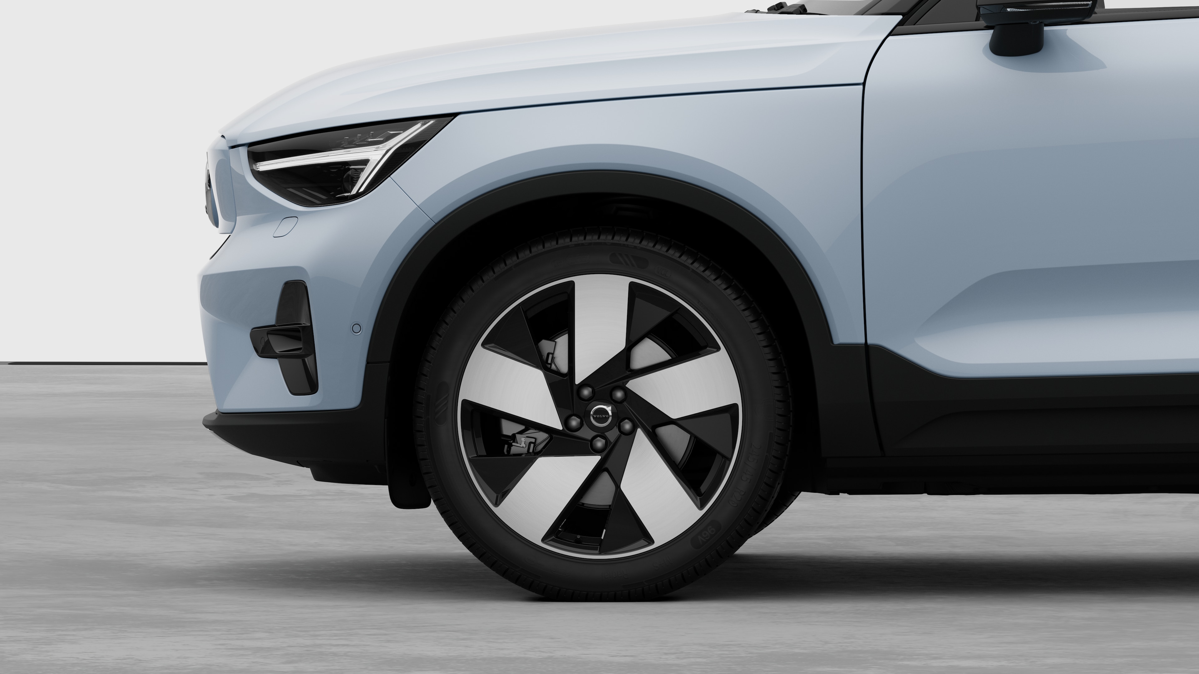 Volvo car exterior side view focusing on the front wheel and fender, set against a plain studio background.