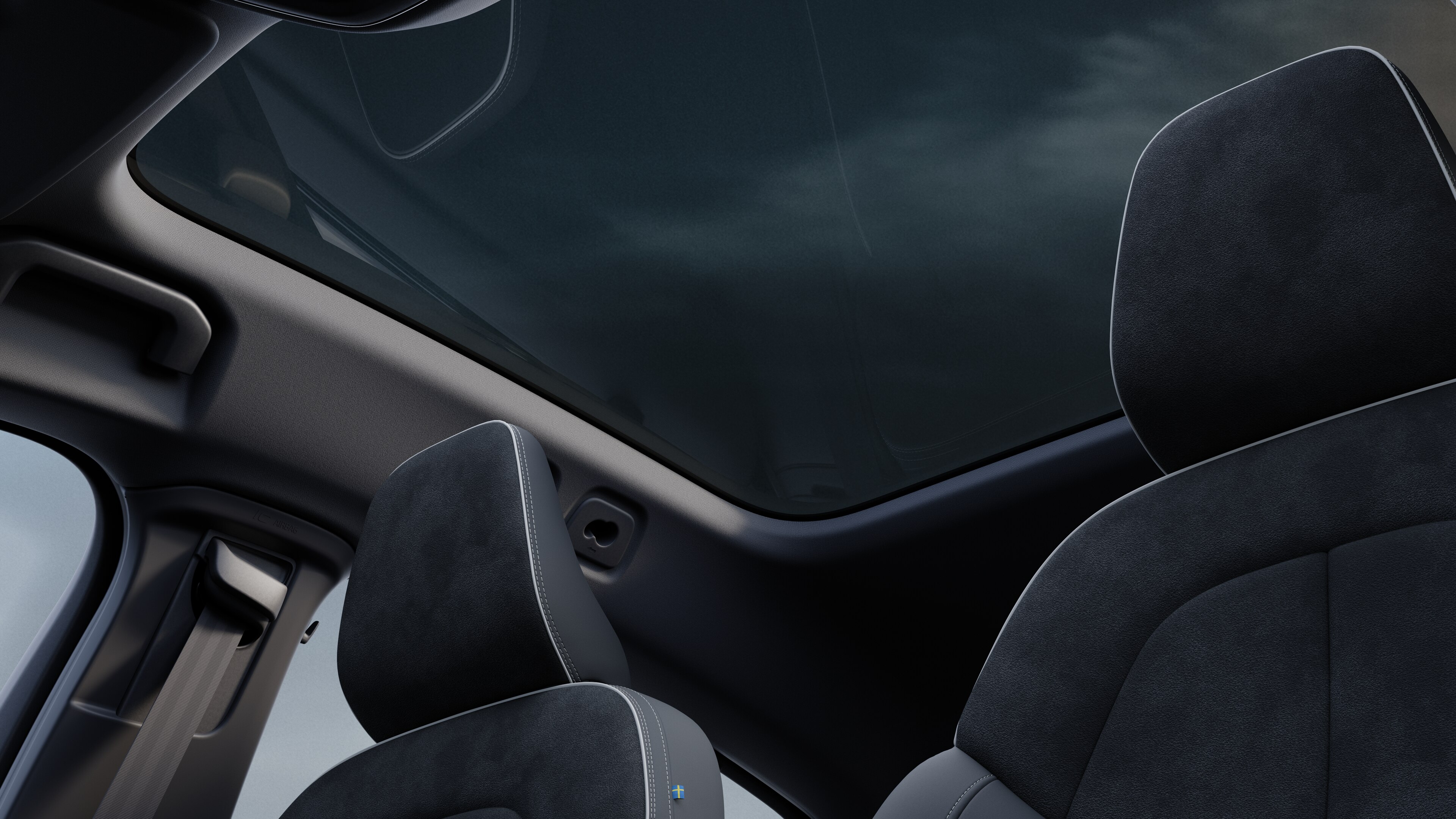 Het interieur van de Volvo met de passagiersstoelen voor- en achterin, het stuur, het dashboard en de middenconsole tegen een effen studioachtergrond.
