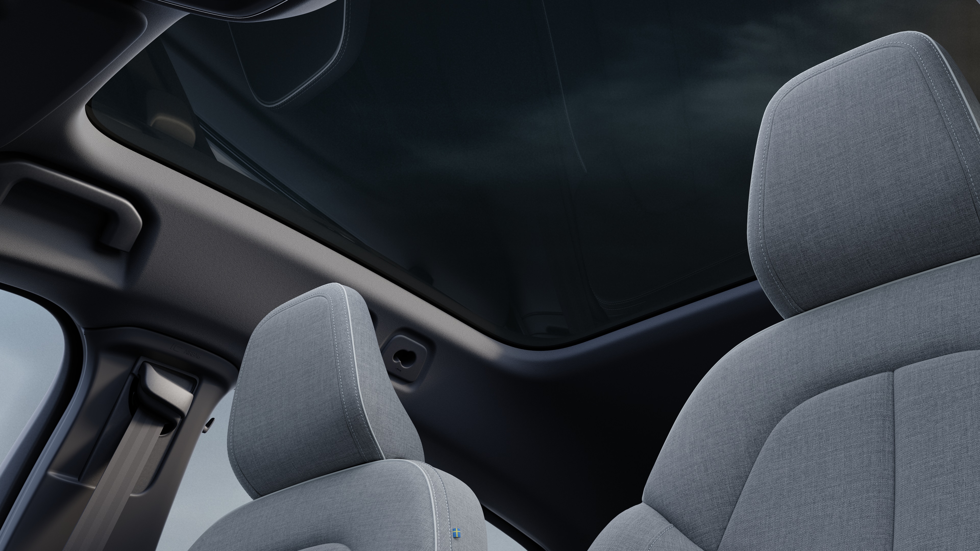 Interior do carro Volvo mostrando os bancos dianteiros e traseiros do passageiro, volante, painel de instrumentos e console central contra um plano de fundo de estúdio.