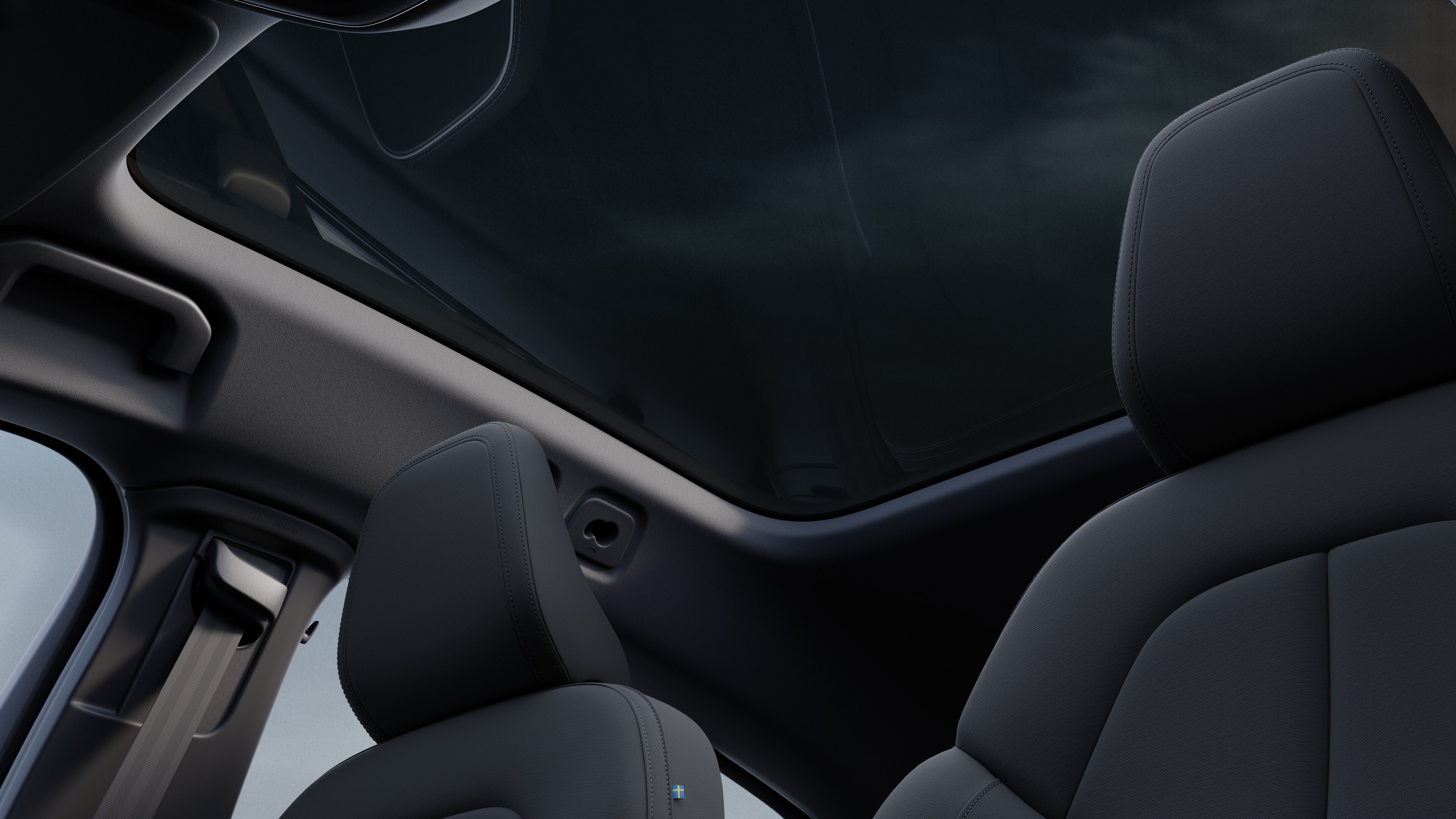 Het interieur van de Volvo met de passagiersstoelen voor- en achterin, het stuur, het dashboard en de middenconsole tegen een effen studioachtergrond.