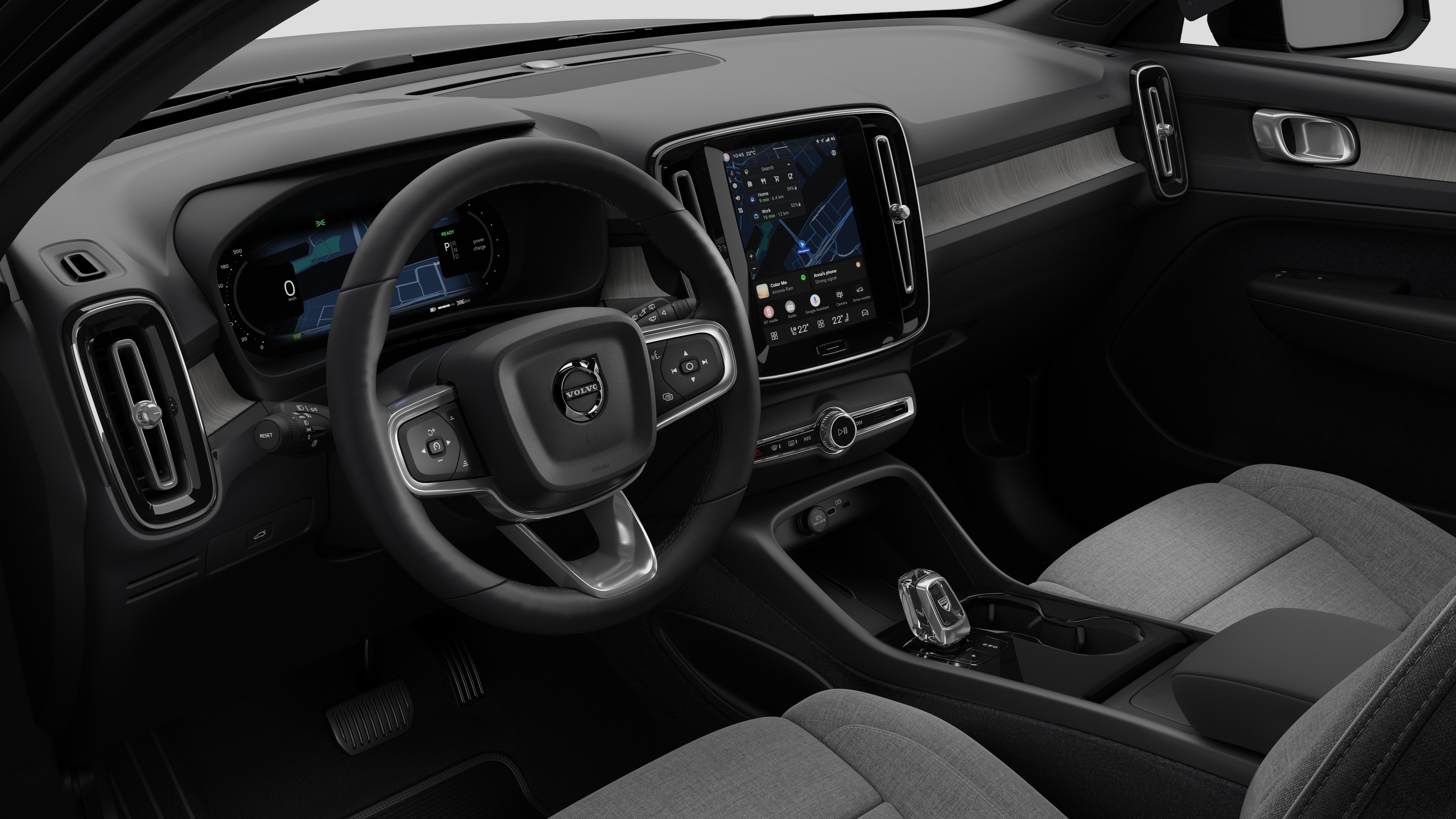 Vista interna de um carro Volvo mostrando o painel, o volante, o console central e a tela digital em um plano de fundo de estúdio simples.