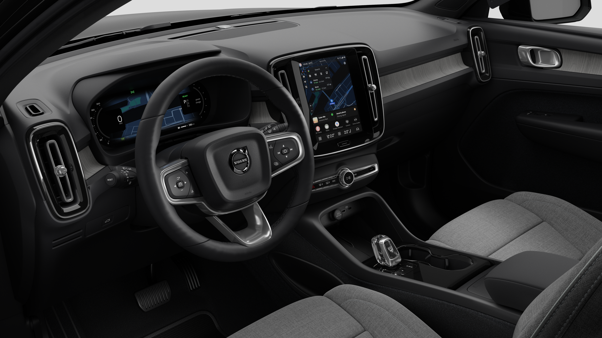 Vista interna de um carro Volvo mostrando o painel, o volante, o console central e a tela digital em um plano de fundo de estúdio simples.