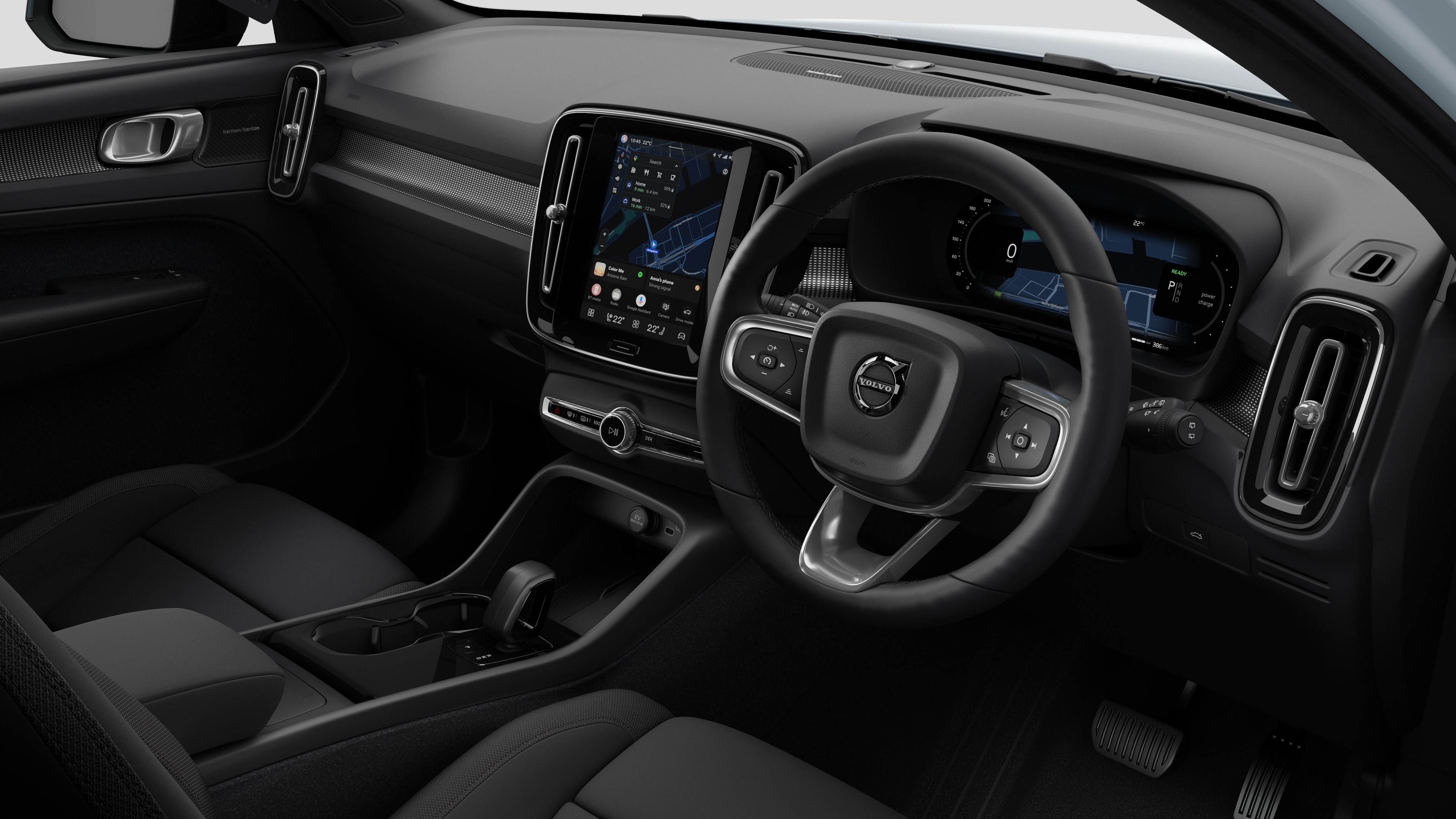 Interior view of a Volvo car showing the dashboard, steering wheel, center console, and digital display screen in a plain studio background.