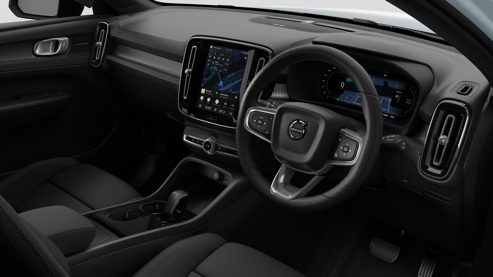 Interior view of a Volvo car showing the dashboard, steering wheel, center console, and digital display screen in a plain studio background.
