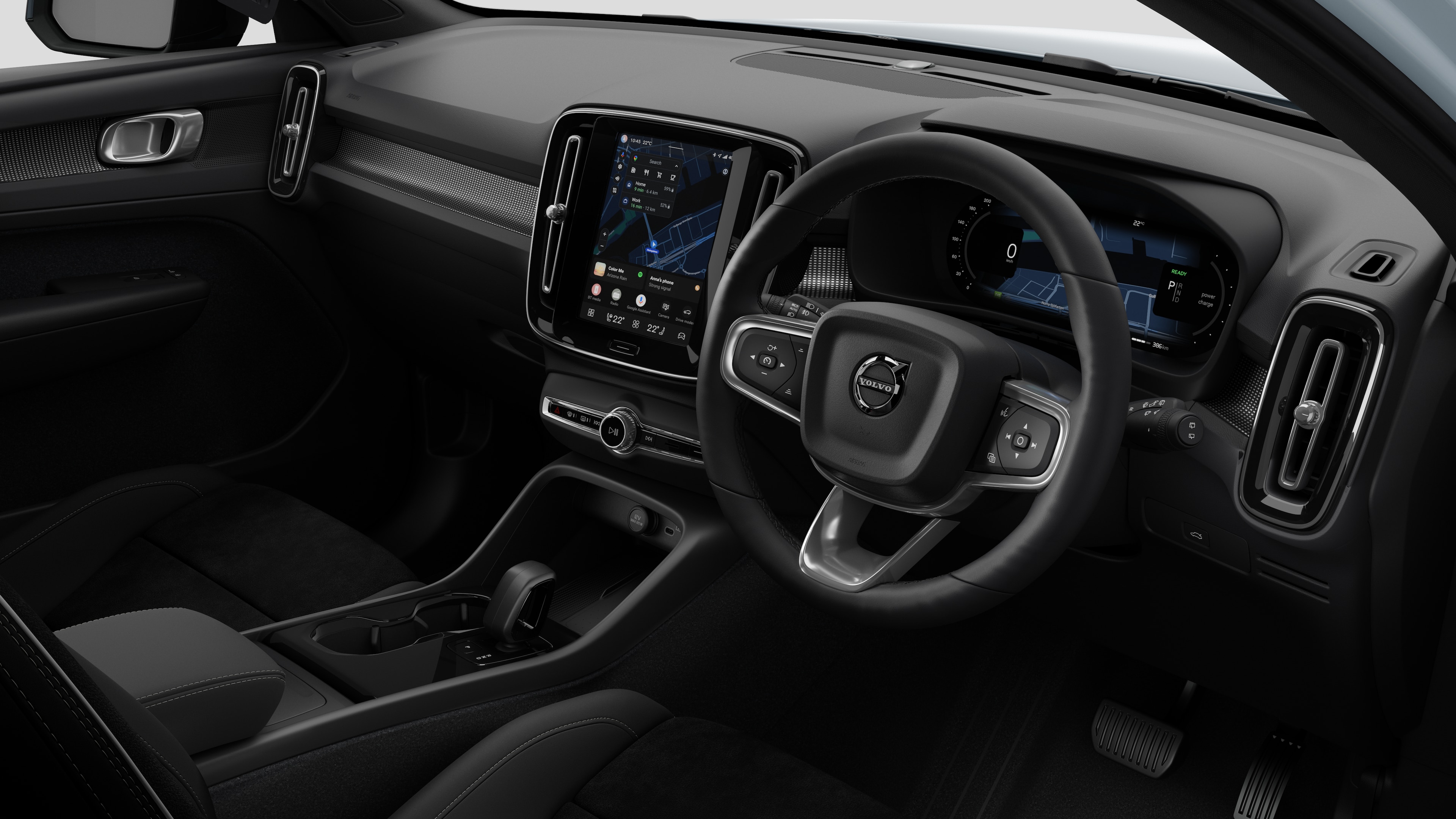 Interior view of a Volvo car showing the dashboard, steering wheel, center console, and digital display screen in a plain studio background.