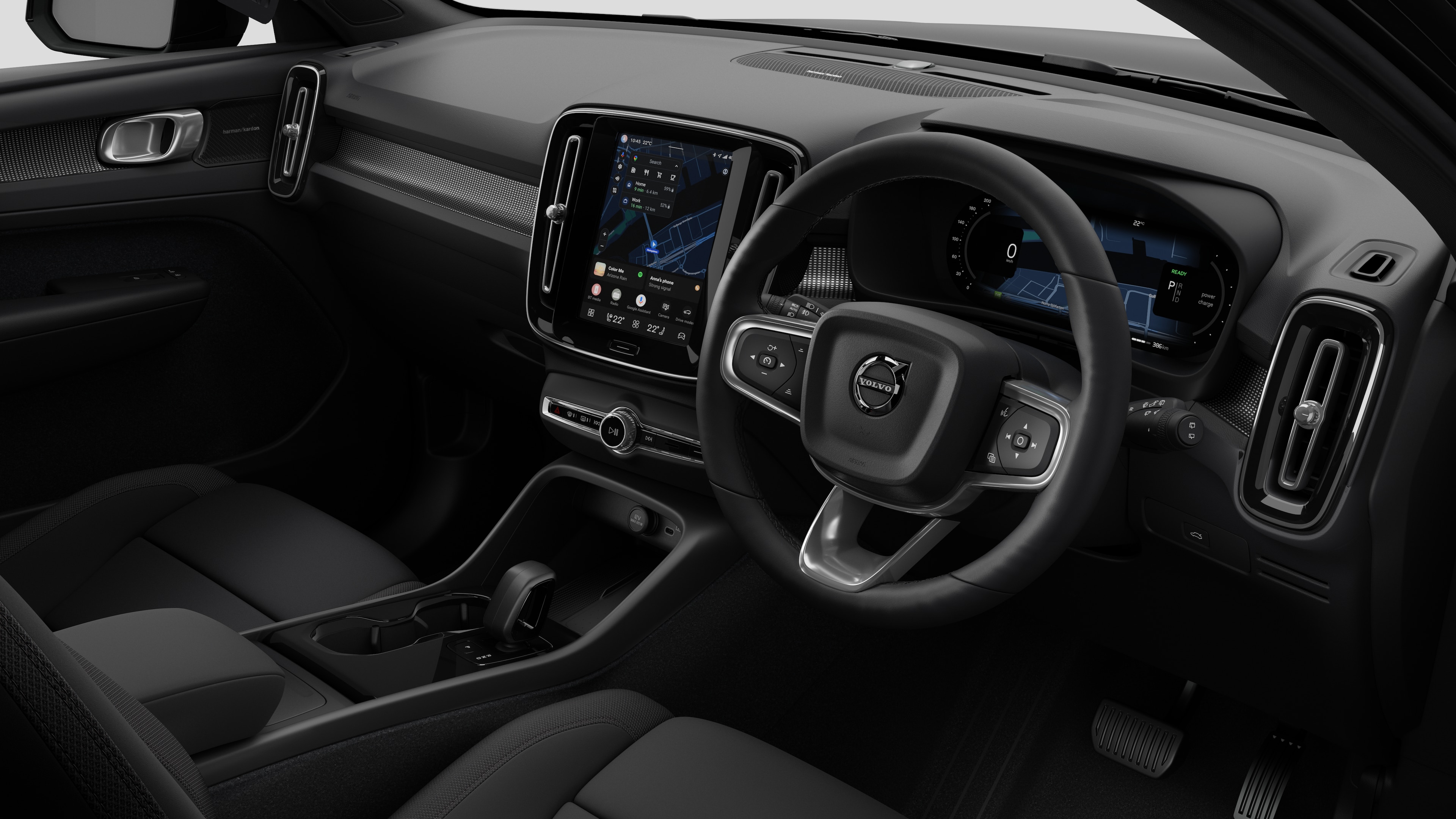 Interior view of a Volvo car showing the dashboard, steering wheel, center console, and digital display screen in a plain studio background.
