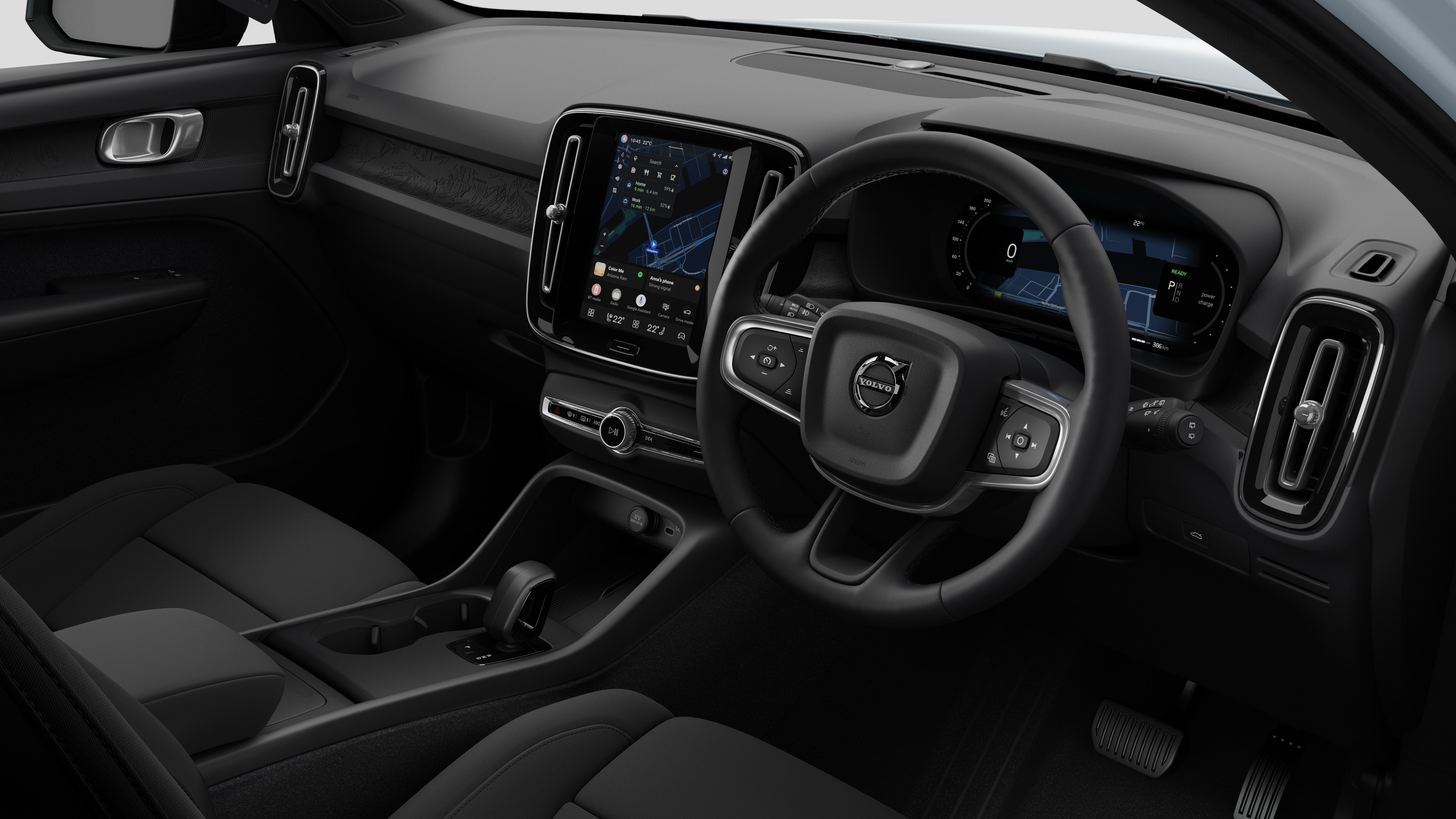 Interior view of a Volvo car showing the dashboard, steering wheel, center console, and digital display screen in a plain studio background.