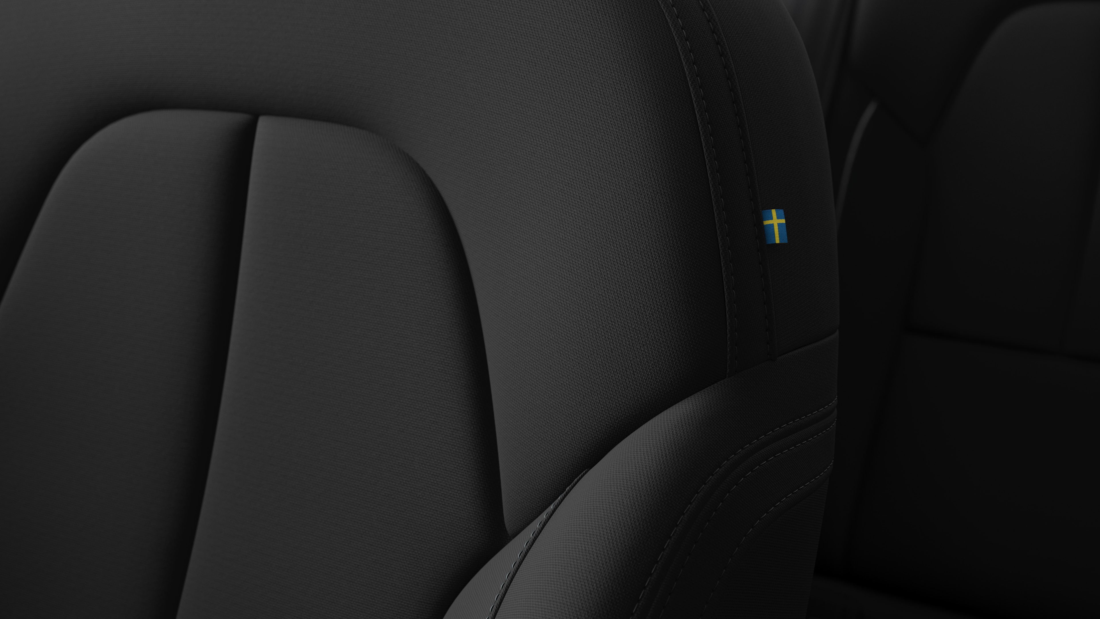 Close-up of Volvo car interior seat detail showing stitching and a small Swedish flag tag.