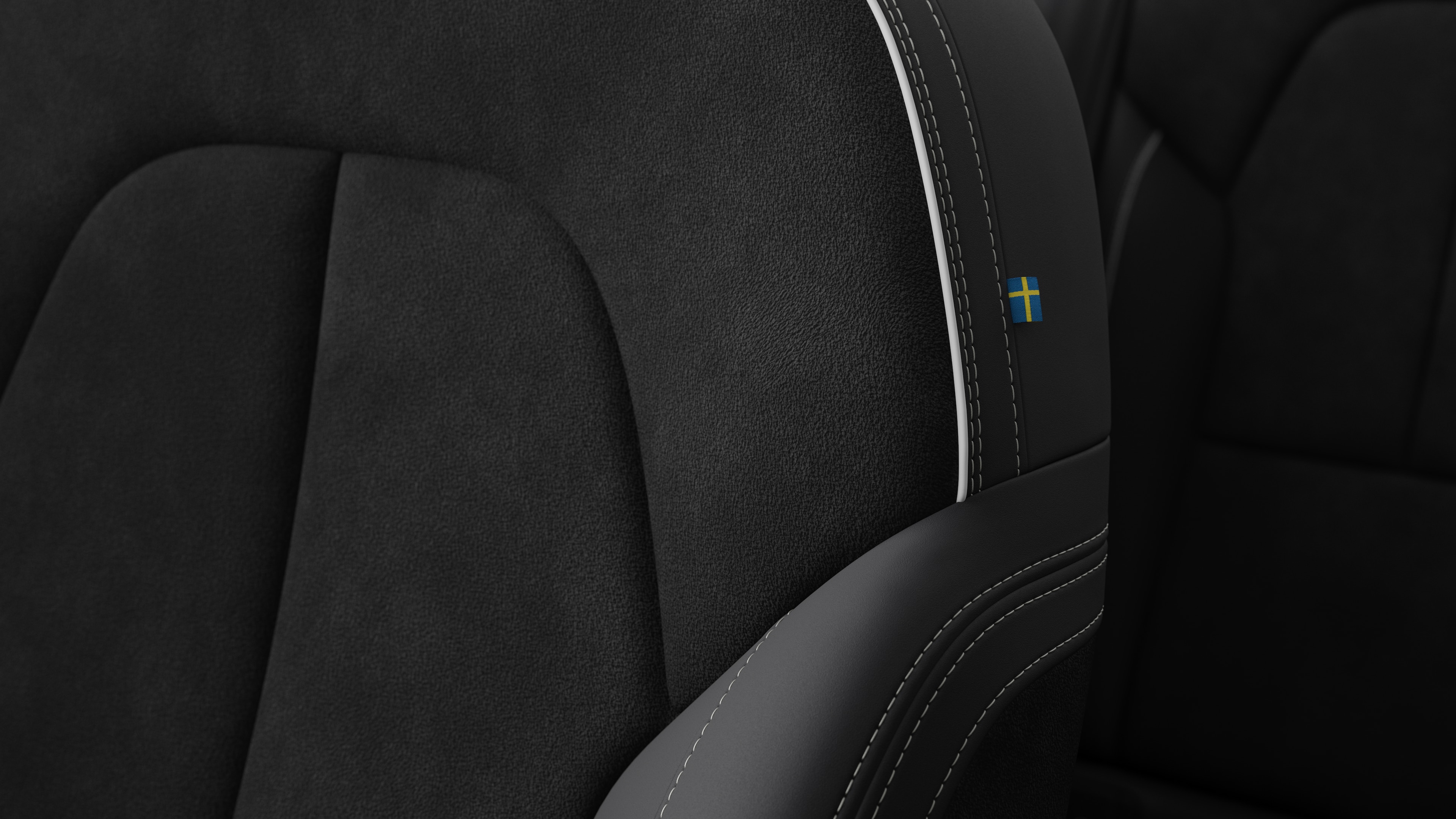 Primer plano del detalle del asiento interior del vehículo Volvo que muestra costuras y una pequeña etiqueta con la bandera sueca.