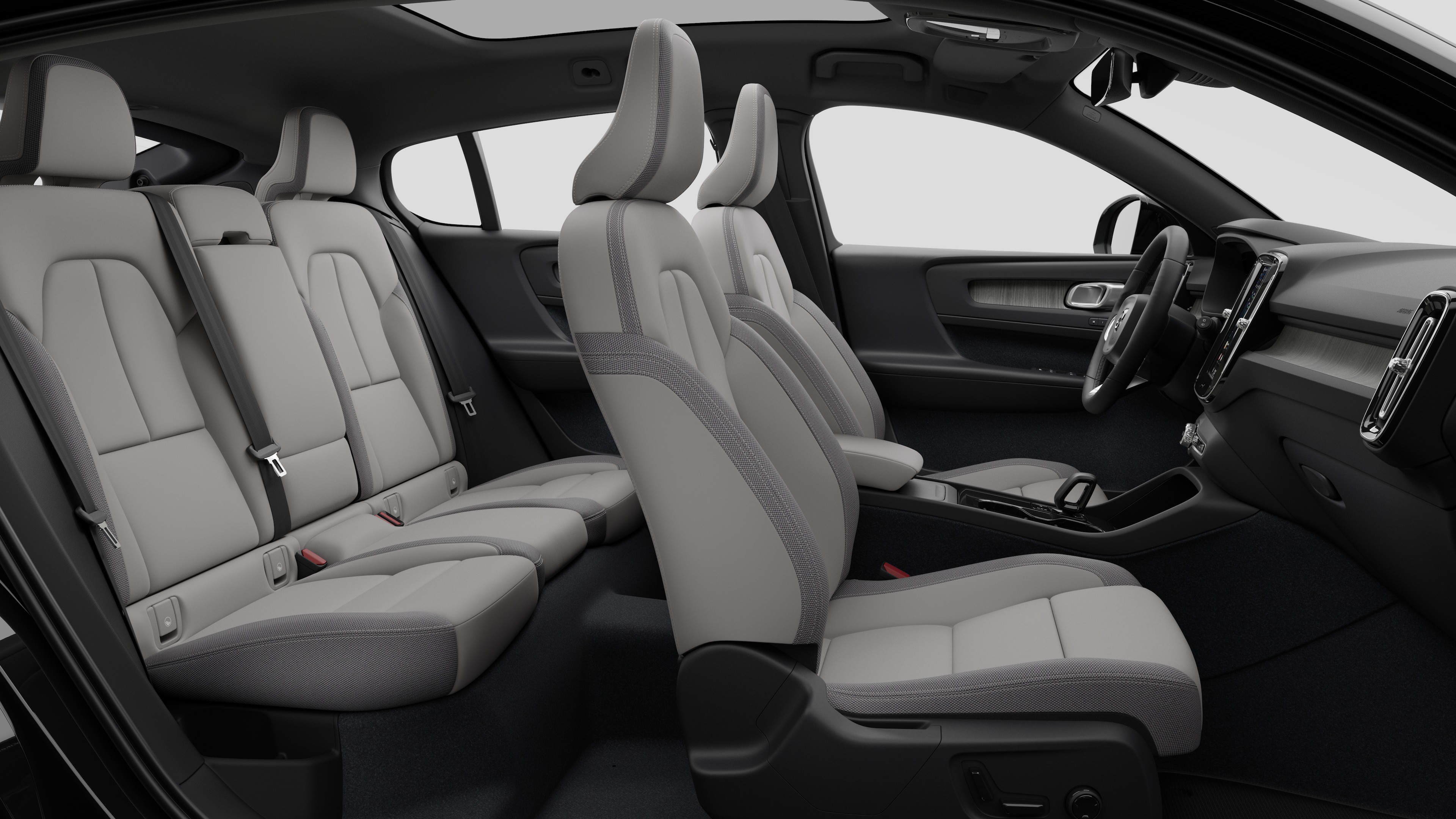 Vista lateral do interior do carro Volvo mostrando os bancos dianteiros, traseiros do passageiro, volante, painel de instrumentos e console central, contra um plano de fundo de estúdio simples.