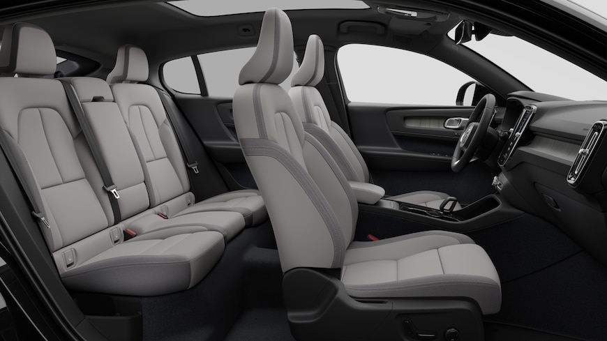 Volvo -auton sisätilojen sivunäkymä, jossa näkyy etuistuimet, takamatkustajan istuimet, ohjauspyörä, kojelauta ja keskikonsoli studiotaustaa vasten.