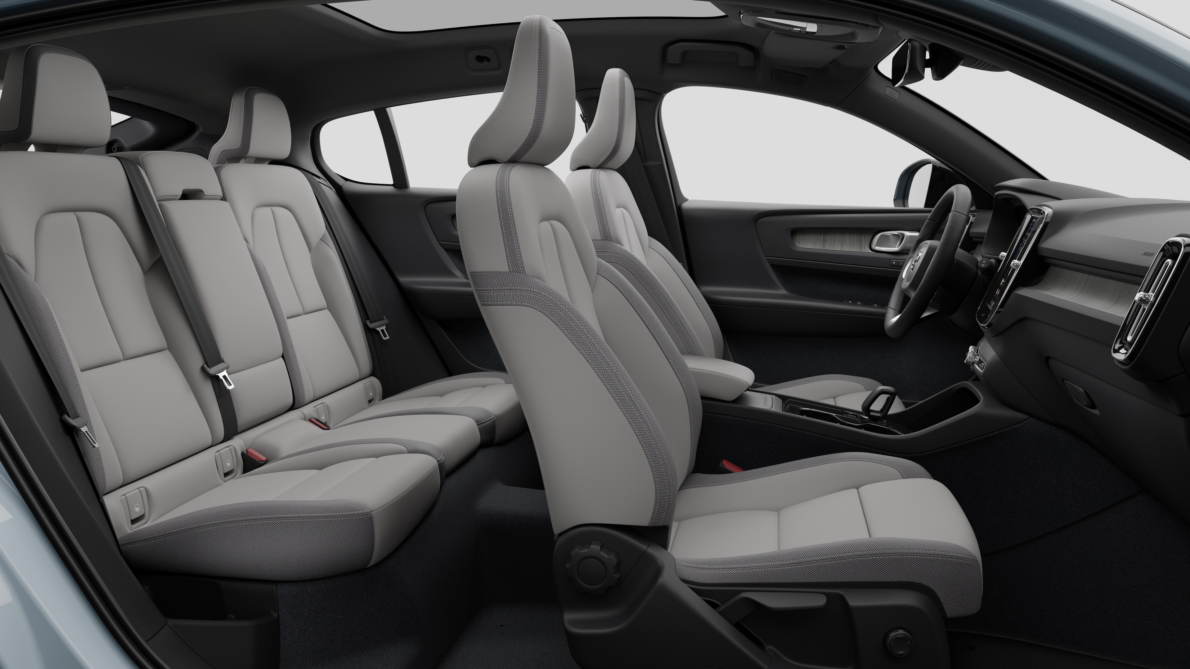 Volvo-bilens interiør set fra siden med forsæder, passagersæder bagi, rat, instrumentbræt og midterkonsol mod almindelig studiebaggrund.