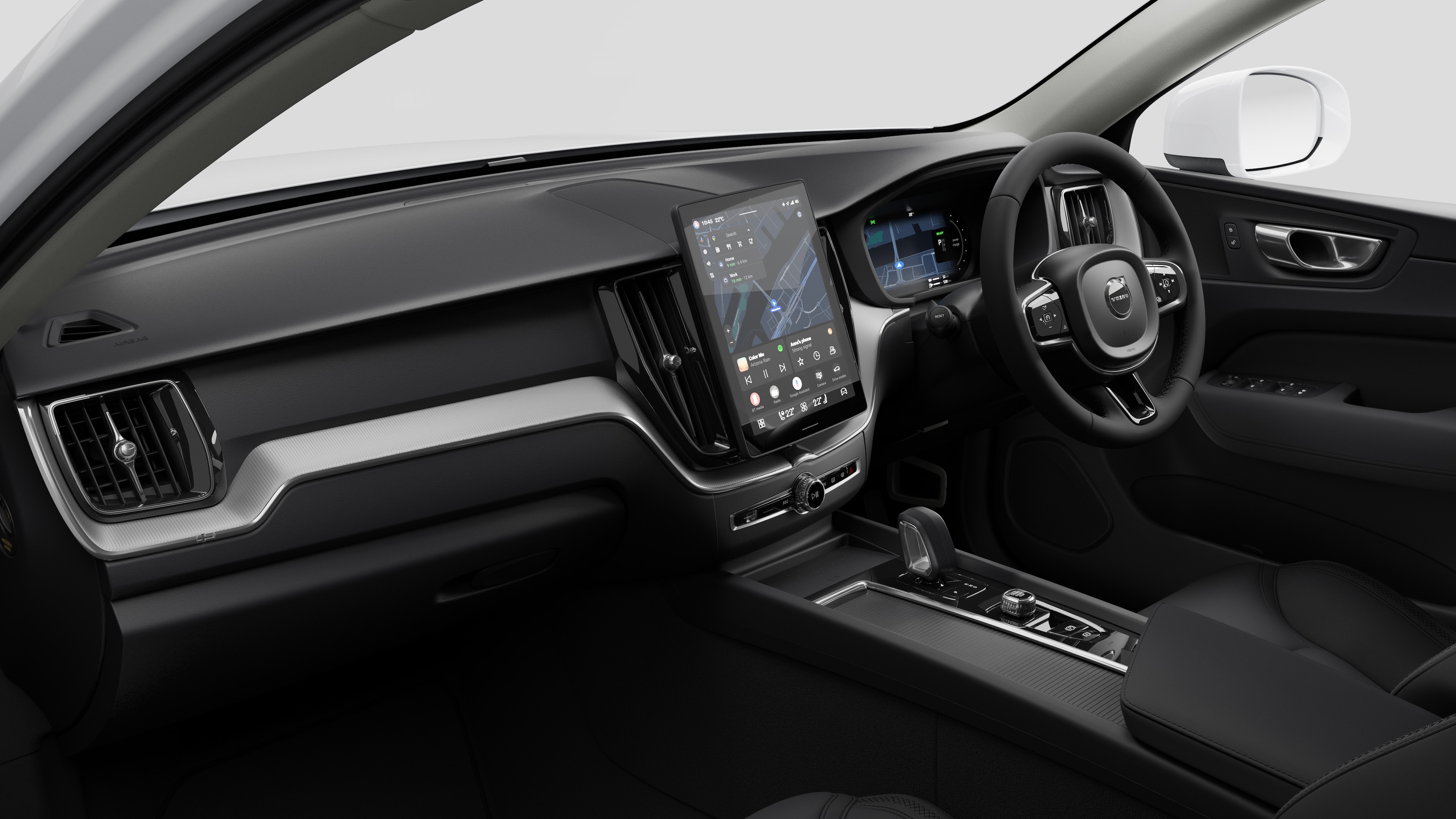 Interior view of a Volvo car showing the dashboard, steering wheel, center console, and digital display screen in a plain studio background.