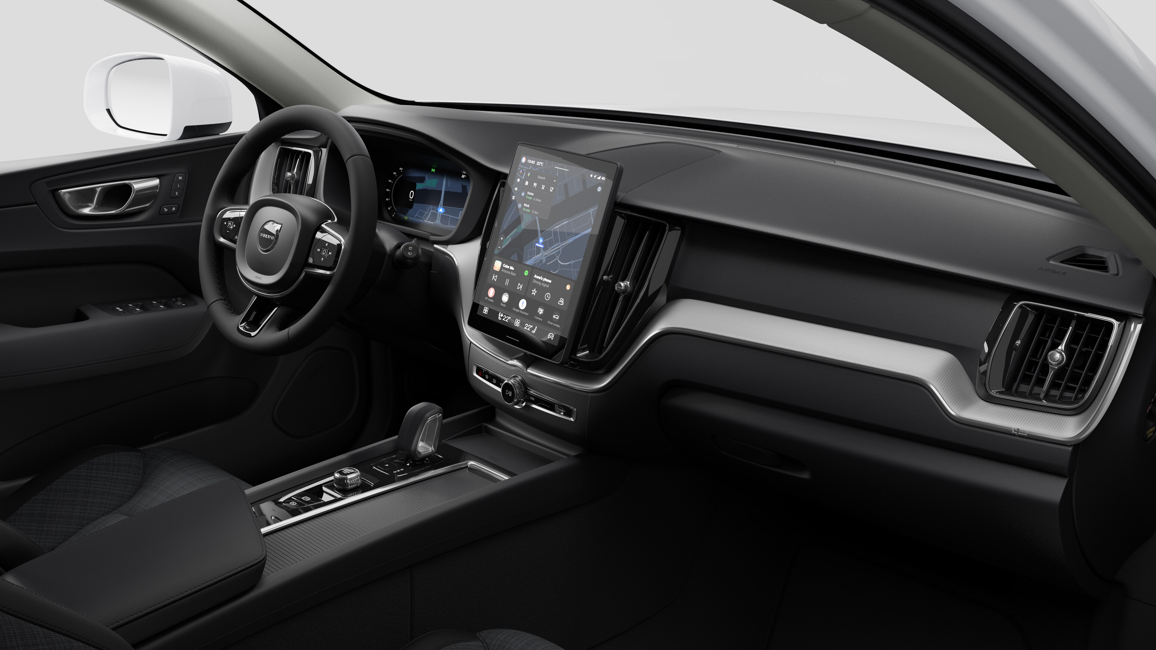 Вид изнутри автомобиля Volvo: приборная панель, руль, центральная консоль и цифровой дисплей на простом студийном фоне.