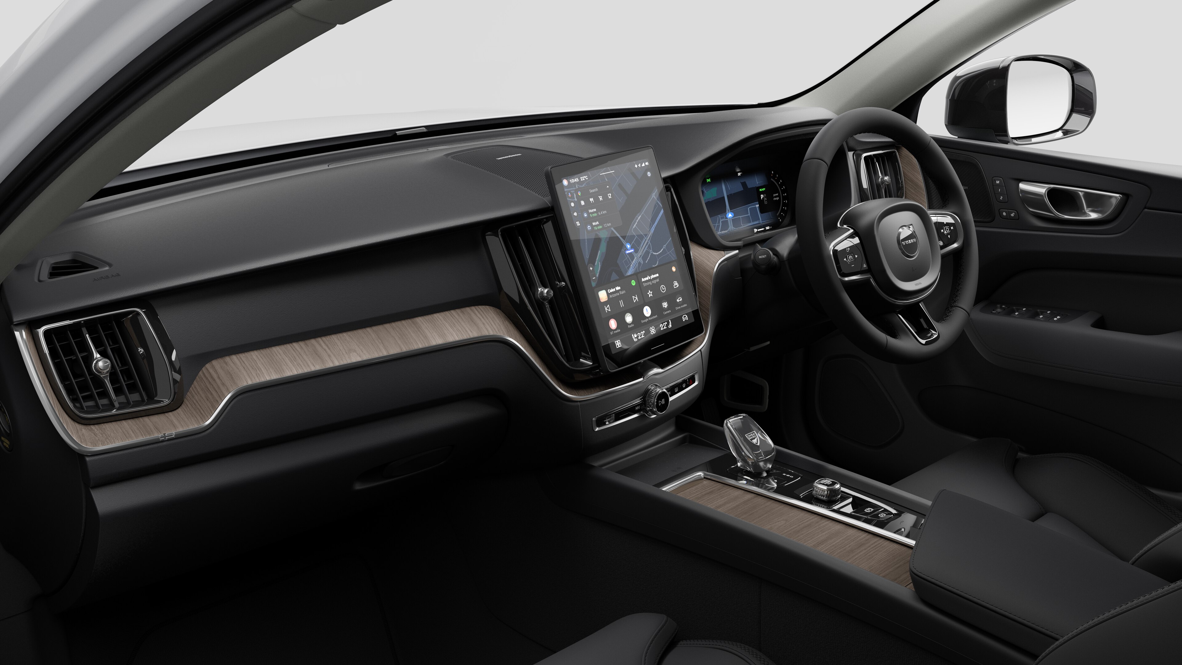 Interior view of a Volvo car showing the dashboard, steering wheel, center console, and digital display screen in a plain studio background.