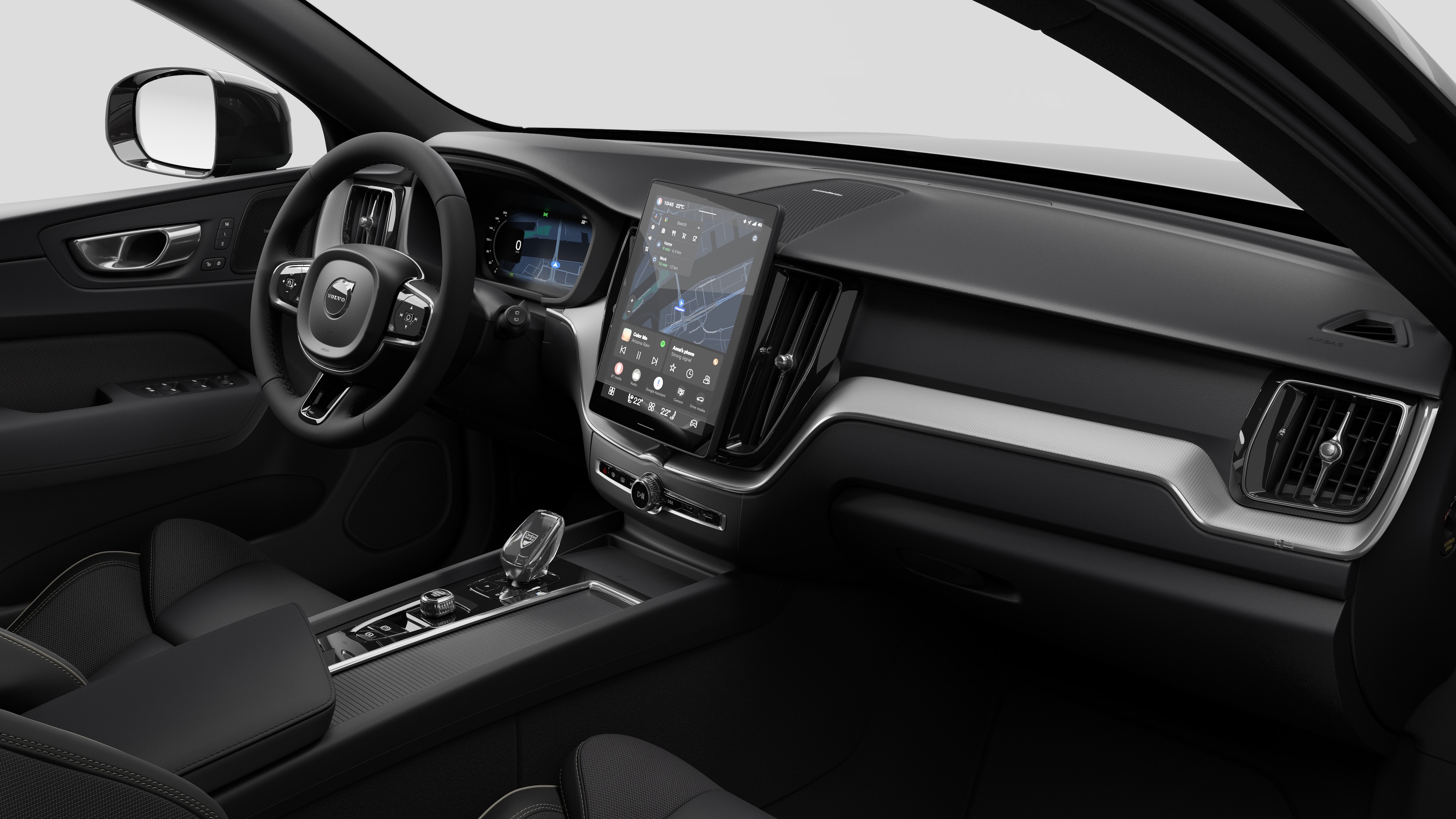 Interior view of a Volvo car showing the dashboard, steering wheel, center console, and digital display screen in a plain studio background.