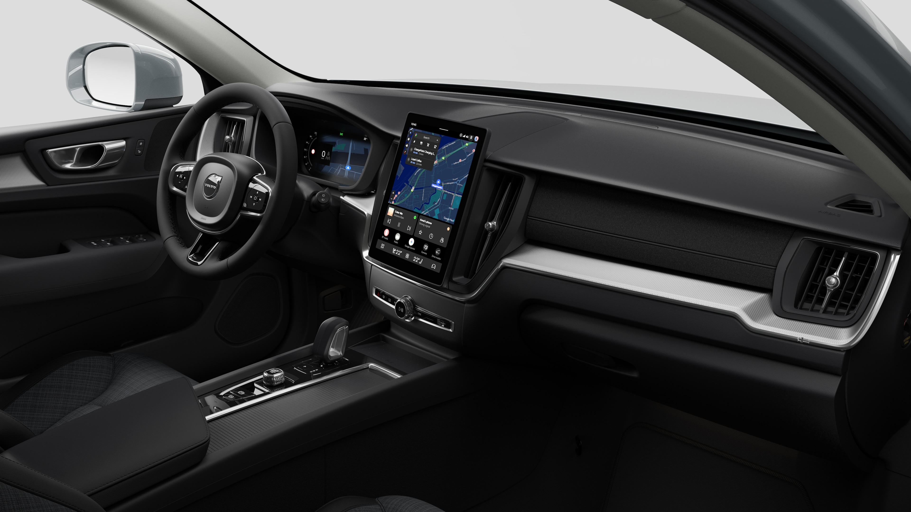 Vue intérieure d’une Volvo montrant le tableau de bord, le volant, la console centrale et l’écran d’affichage numérique dans un fond de studio uni.