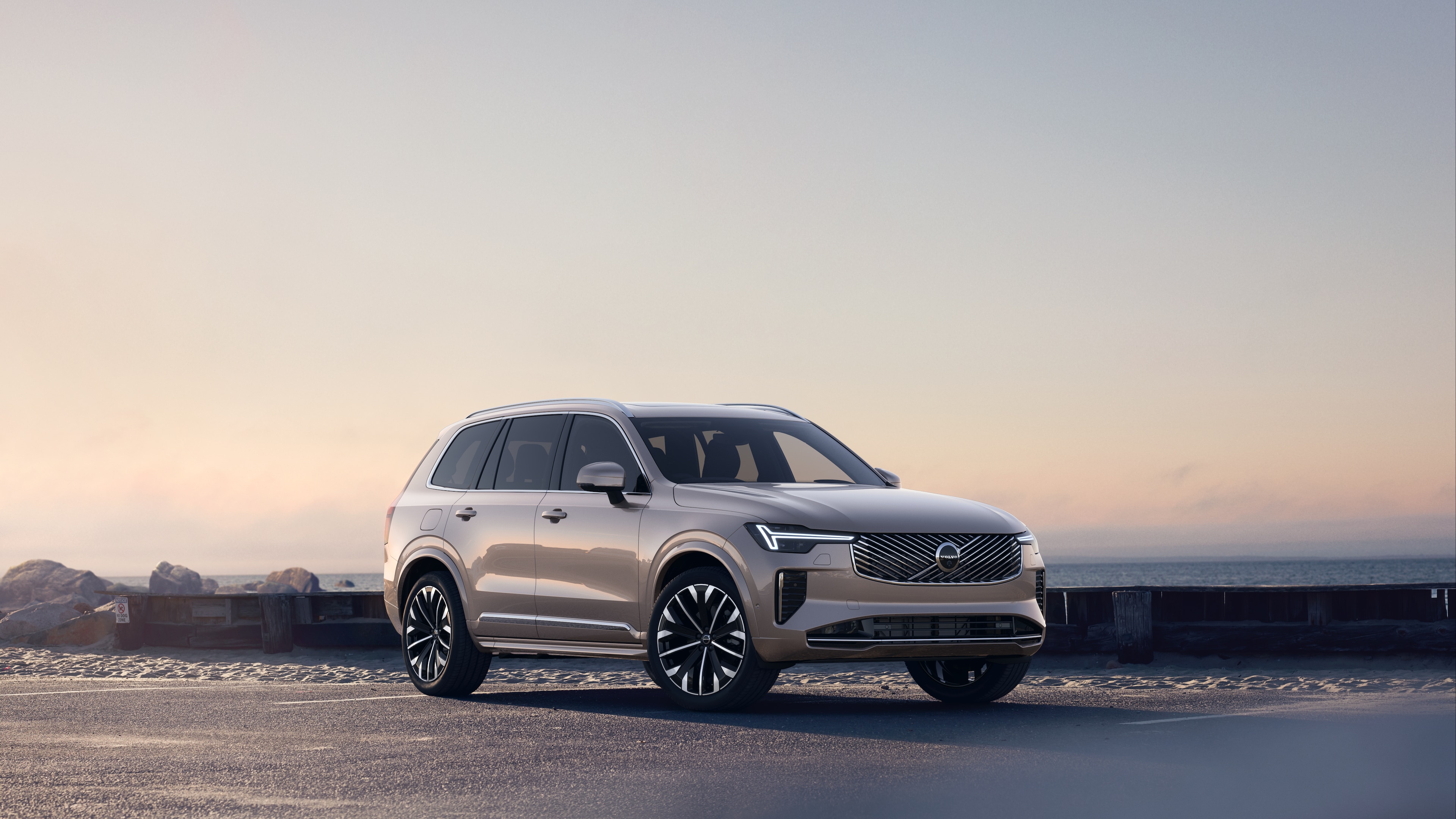 Volvo car in three-quarter view on coastal road, showing the front and side against a serene ocean background.