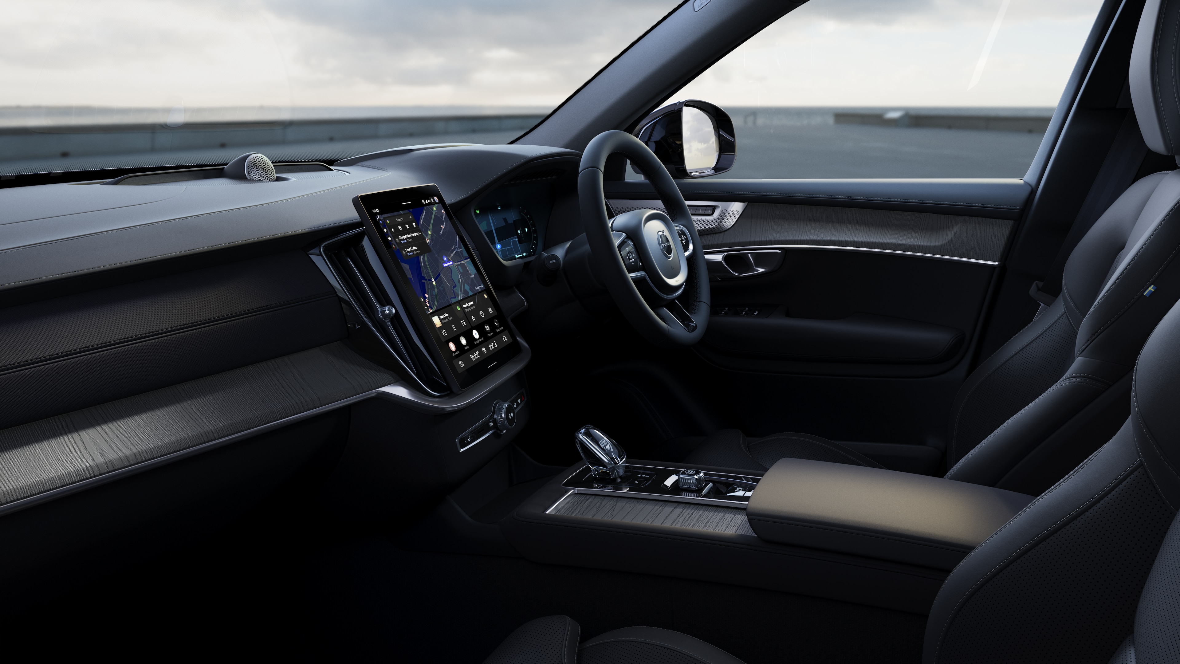 Volvo car interior showing dashboard, steering wheel, and center console with digital display in an open road background.