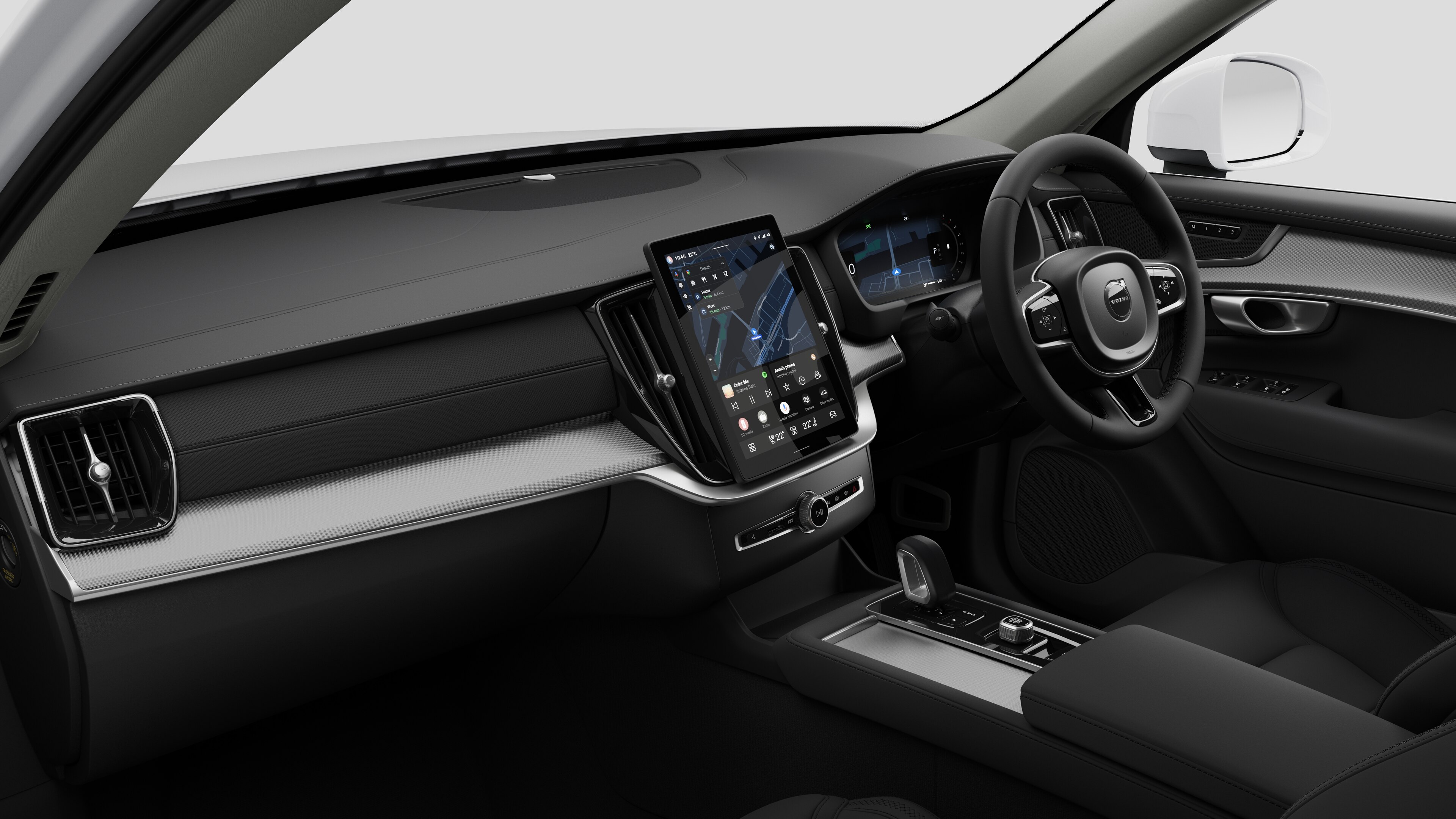 Interior view of a Volvo car showing the dashboard, steering wheel, center console, and digital display screen in a plain studio background.