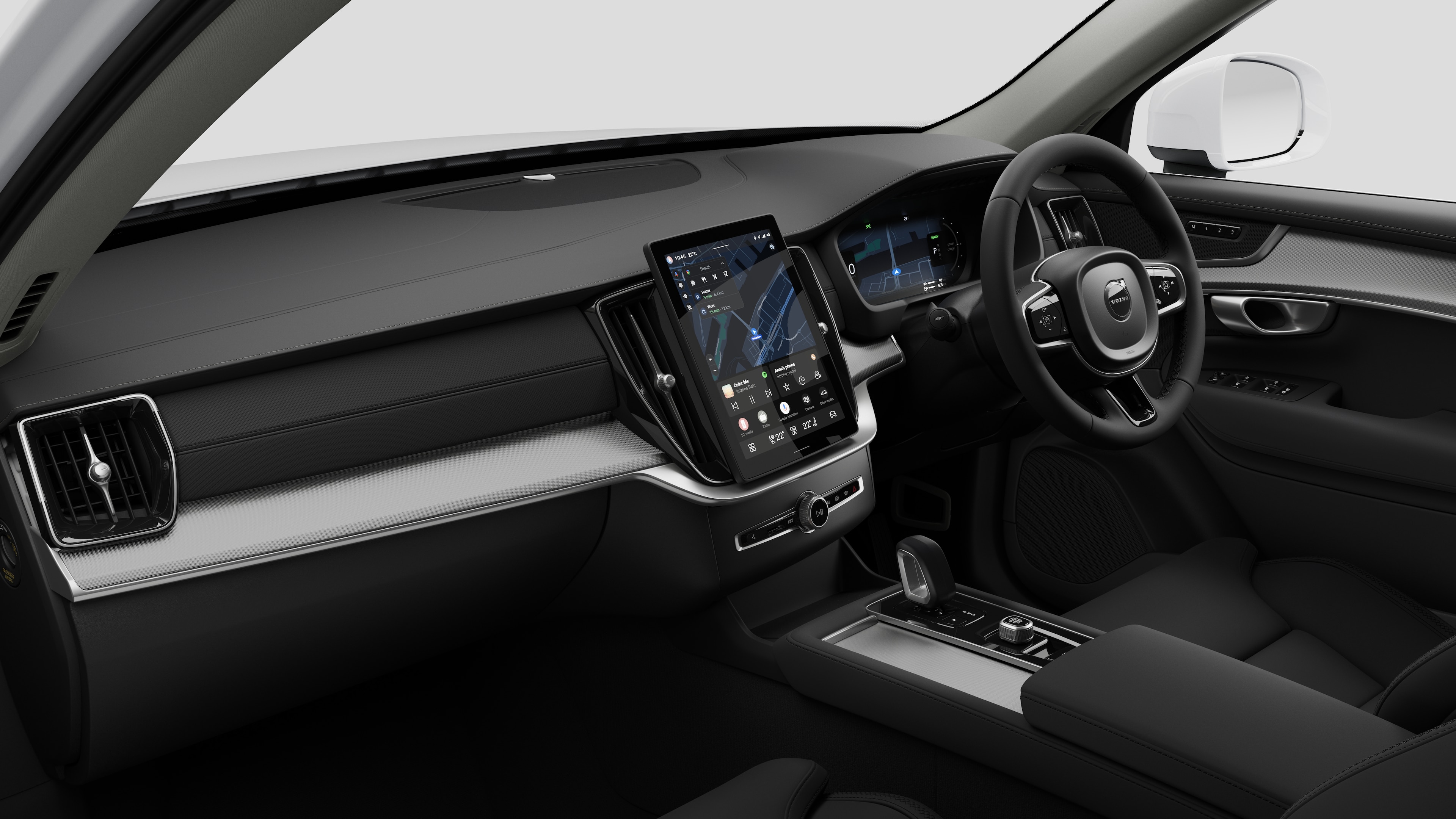 Interior view of a Volvo car showing the dashboard, steering wheel, center console, and digital display screen in a plain studio background.