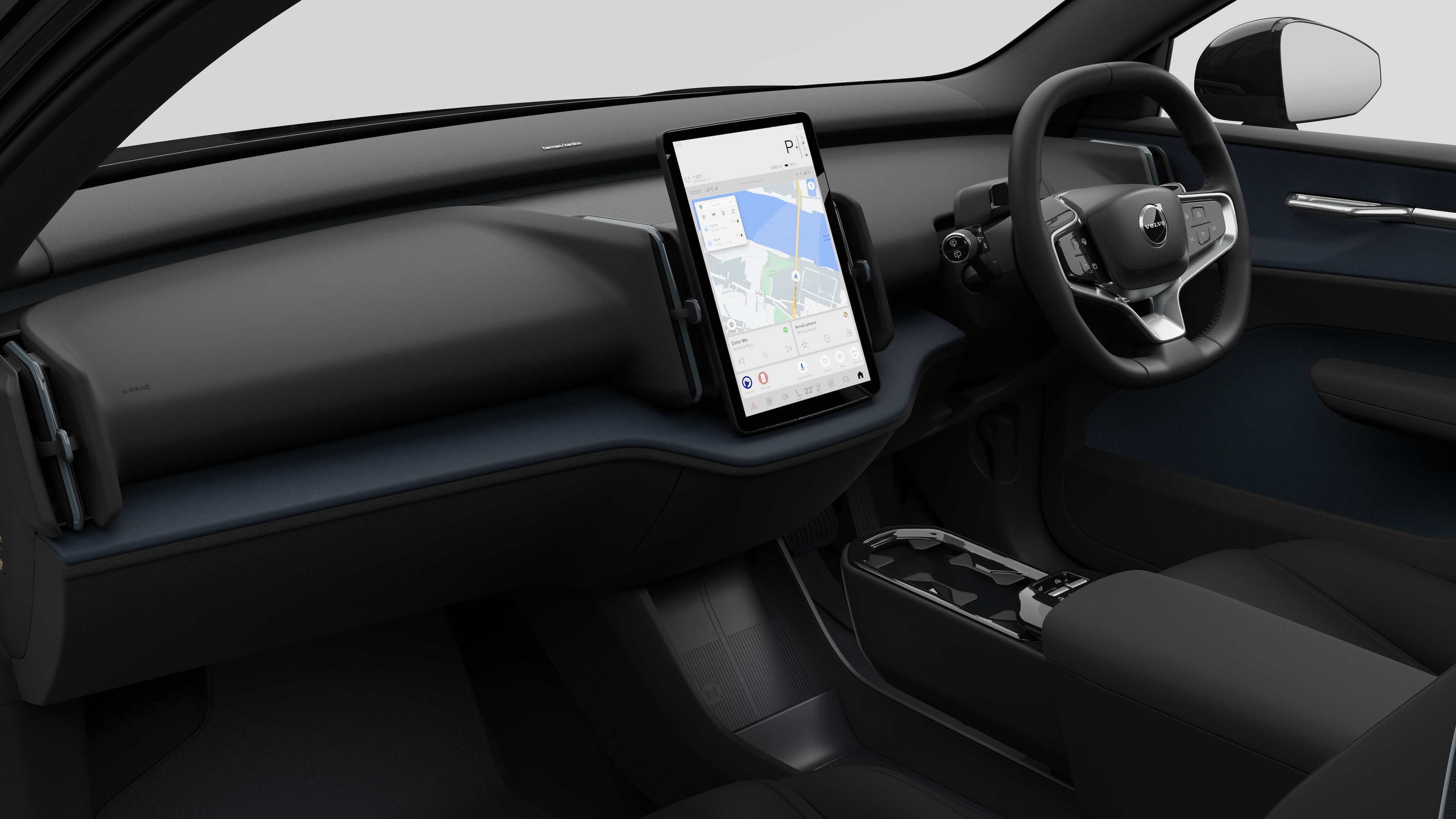 Interior view of a Volvo car showing the dashboard, steering wheel, centre console, and digital display screen in a plain studio background.