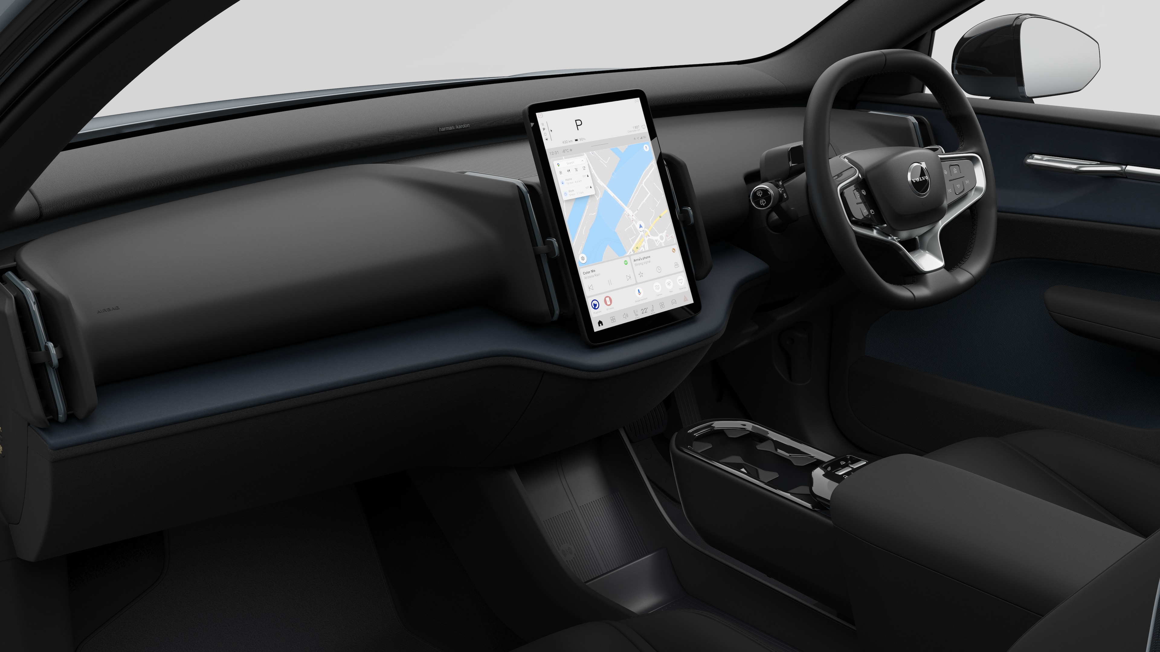 Interior view of a Volvo car showing the dashboard, steering wheel, center console, and digital display screen in a plain studio background.