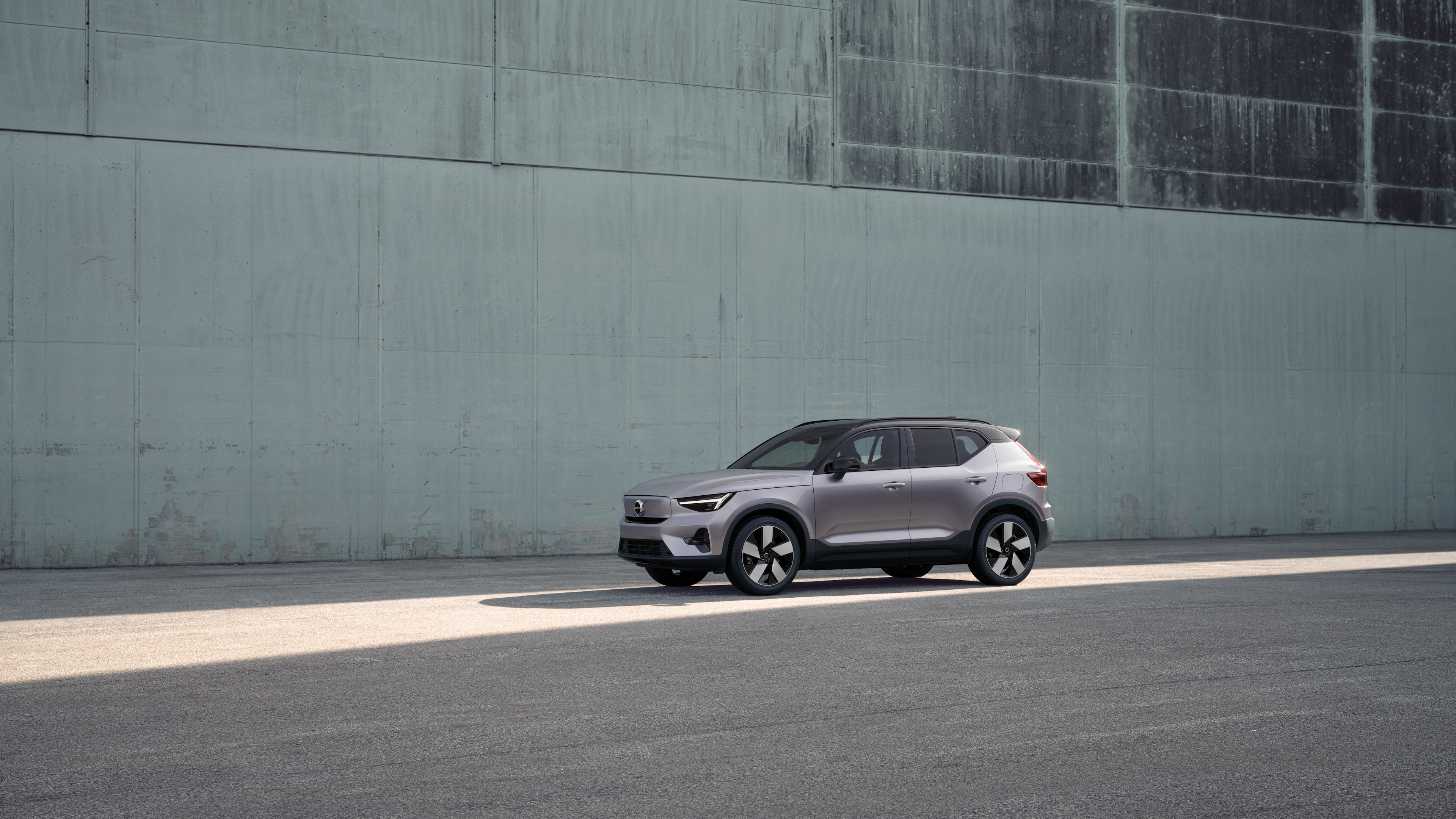 Exterior do carro Volvo em vista de três quartos contra um fundo de parede de concreto industrial.