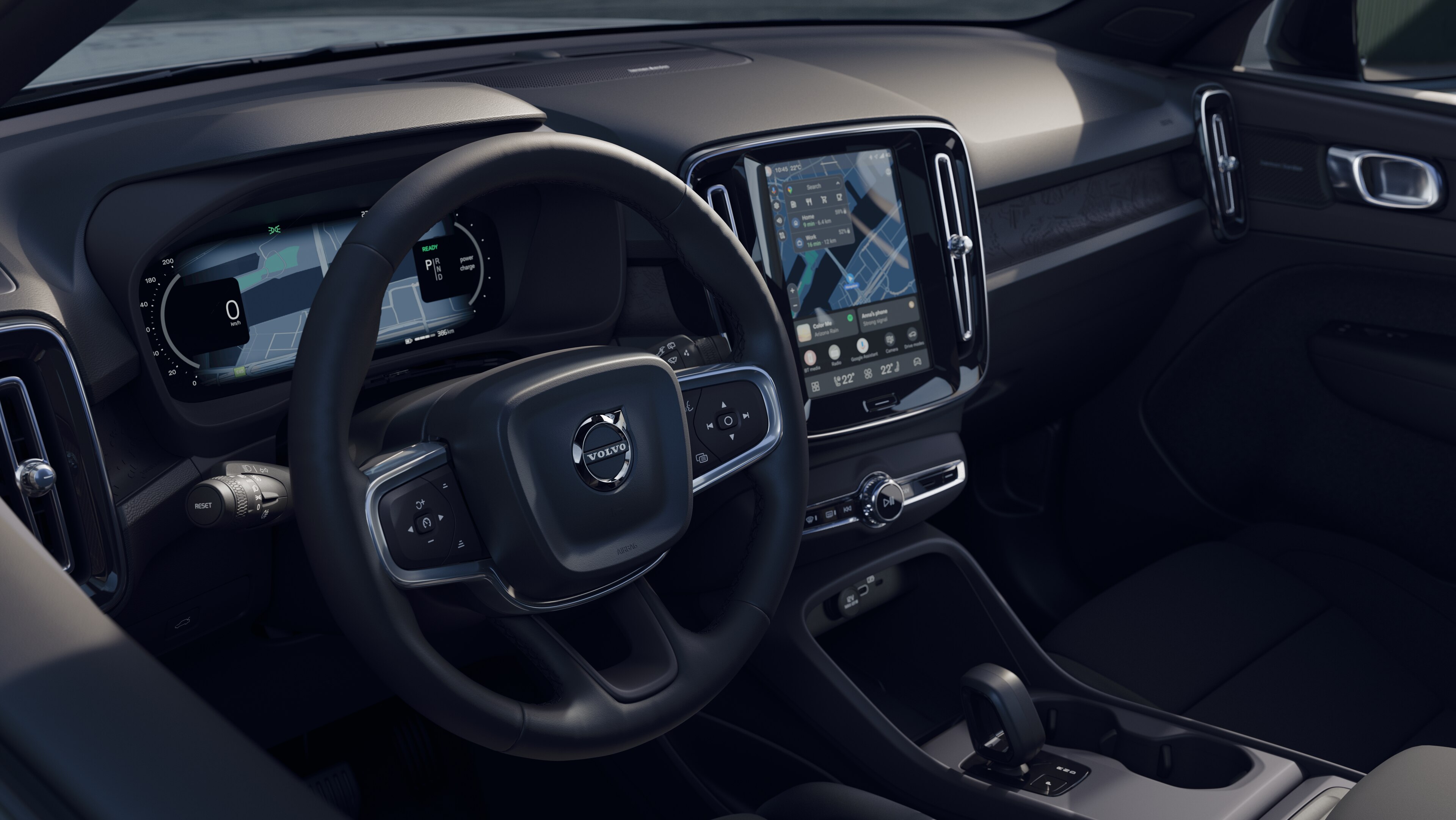 Interno di un'auto Volvo che mostra cruscotto, volante e console centrale con display digitale sullo sfondo di una strada aperta.