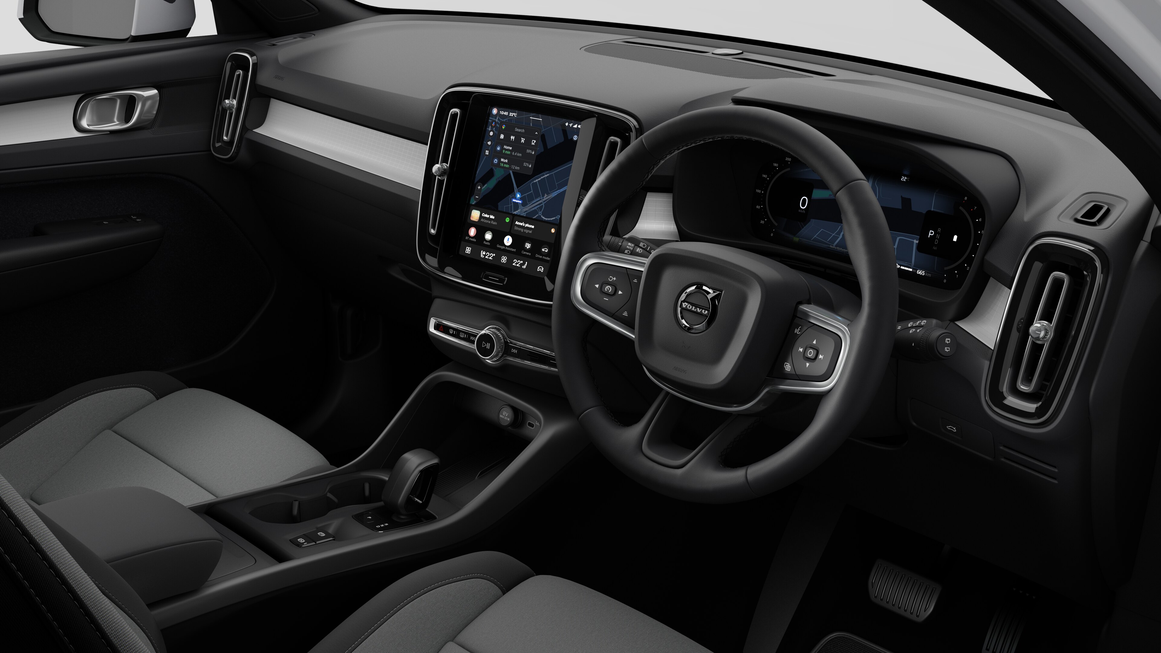 Interior view of a Volvo car showing the dashboard, steering wheel, center console, and digital display screen in a plain studio background.
