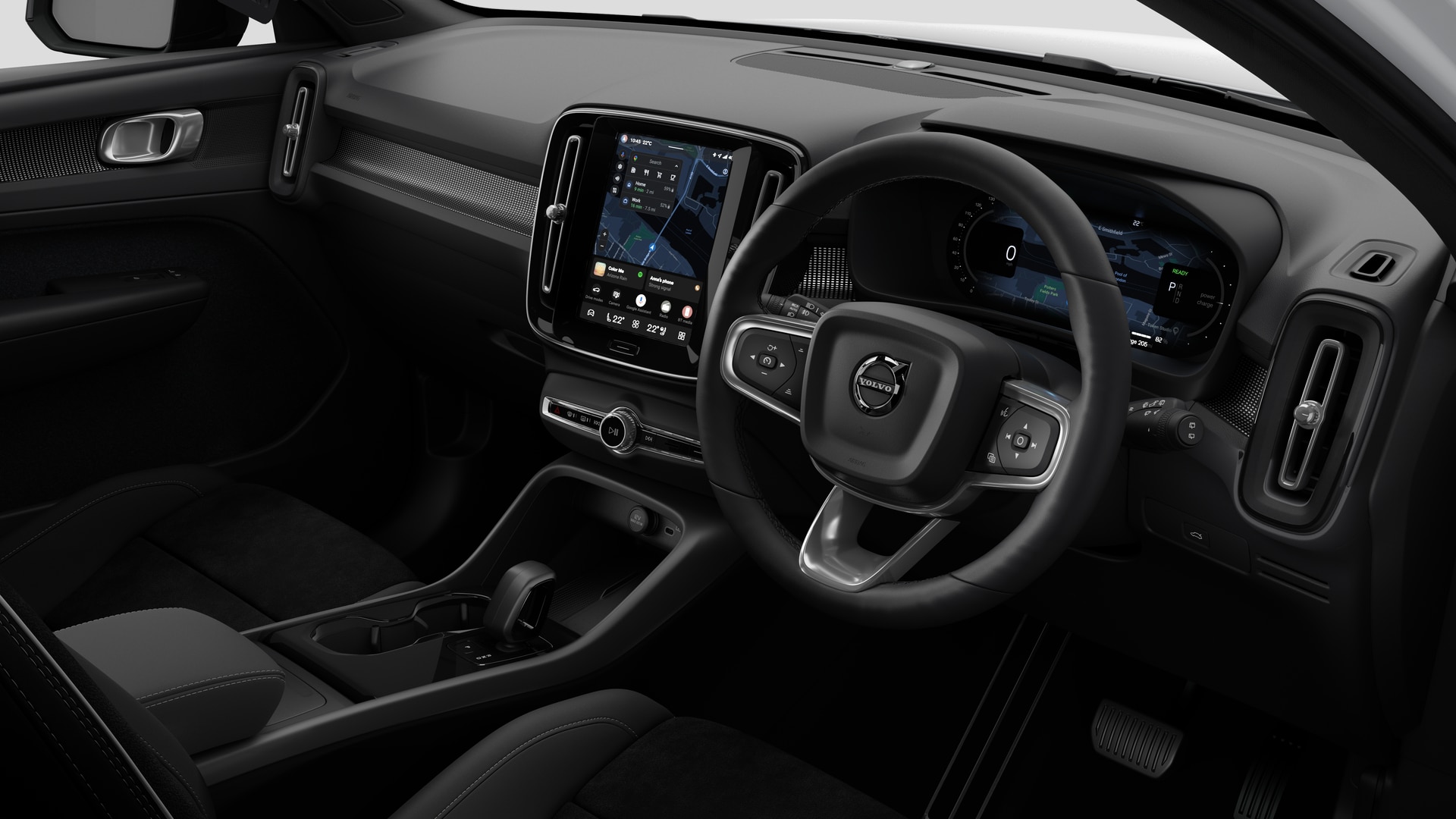 Interior view of a Volvo car showing the dashboard, steering wheel, centre console, and digital display screen in a plain studio background.